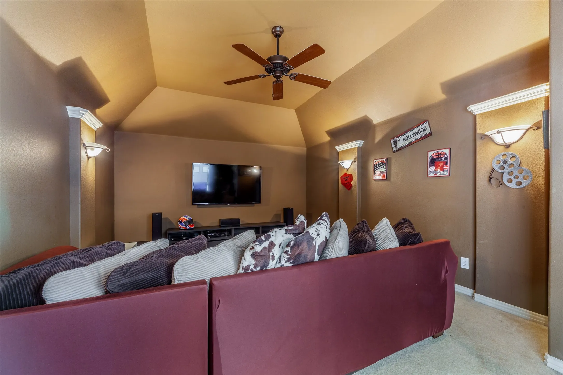 Carpeted cinema room with ceiling fan