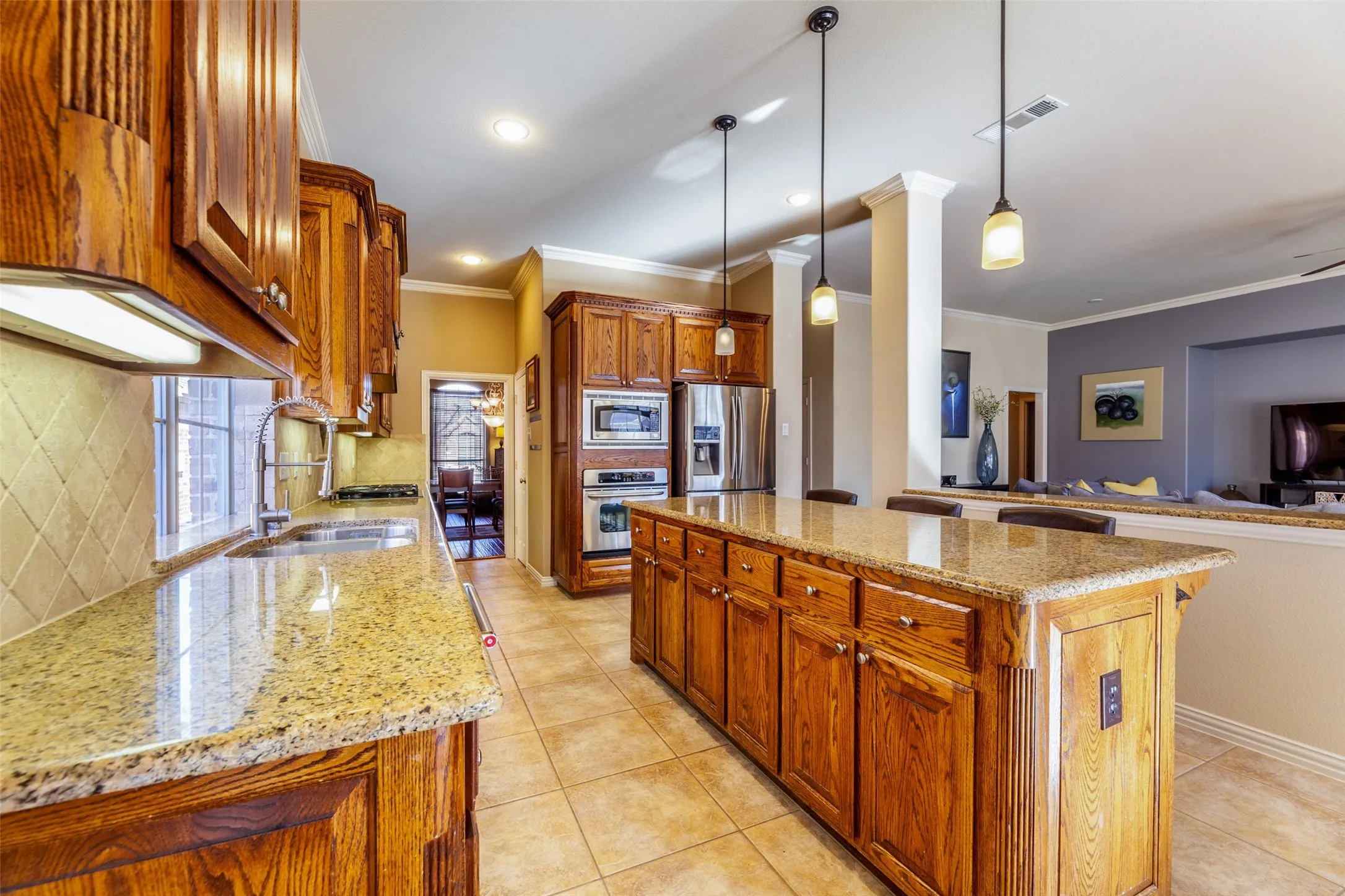 Kitchen featuring ornamental molding, light stone countertops, appliances with stainless steel finishes, and a sink