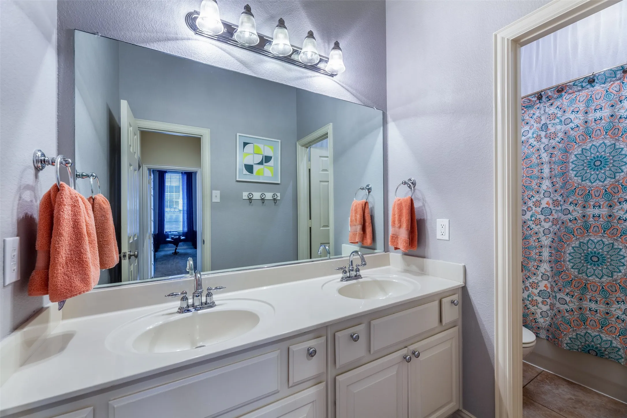 Full bathroom featuring double vanity, toilet, a shower with curtain, and a sink