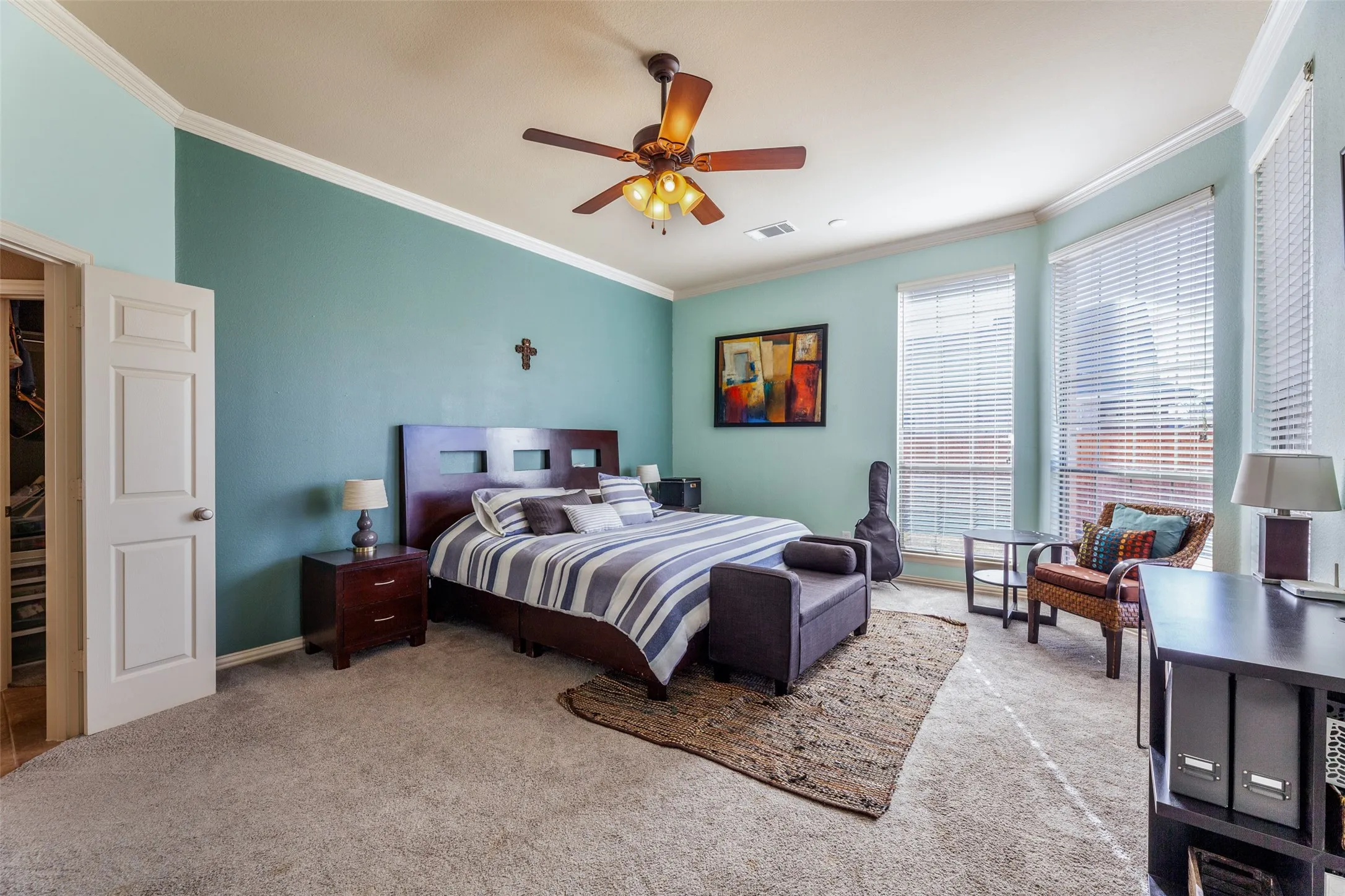 Carpeted bedroom featuring ceiling fan, visible vents, and crown molding