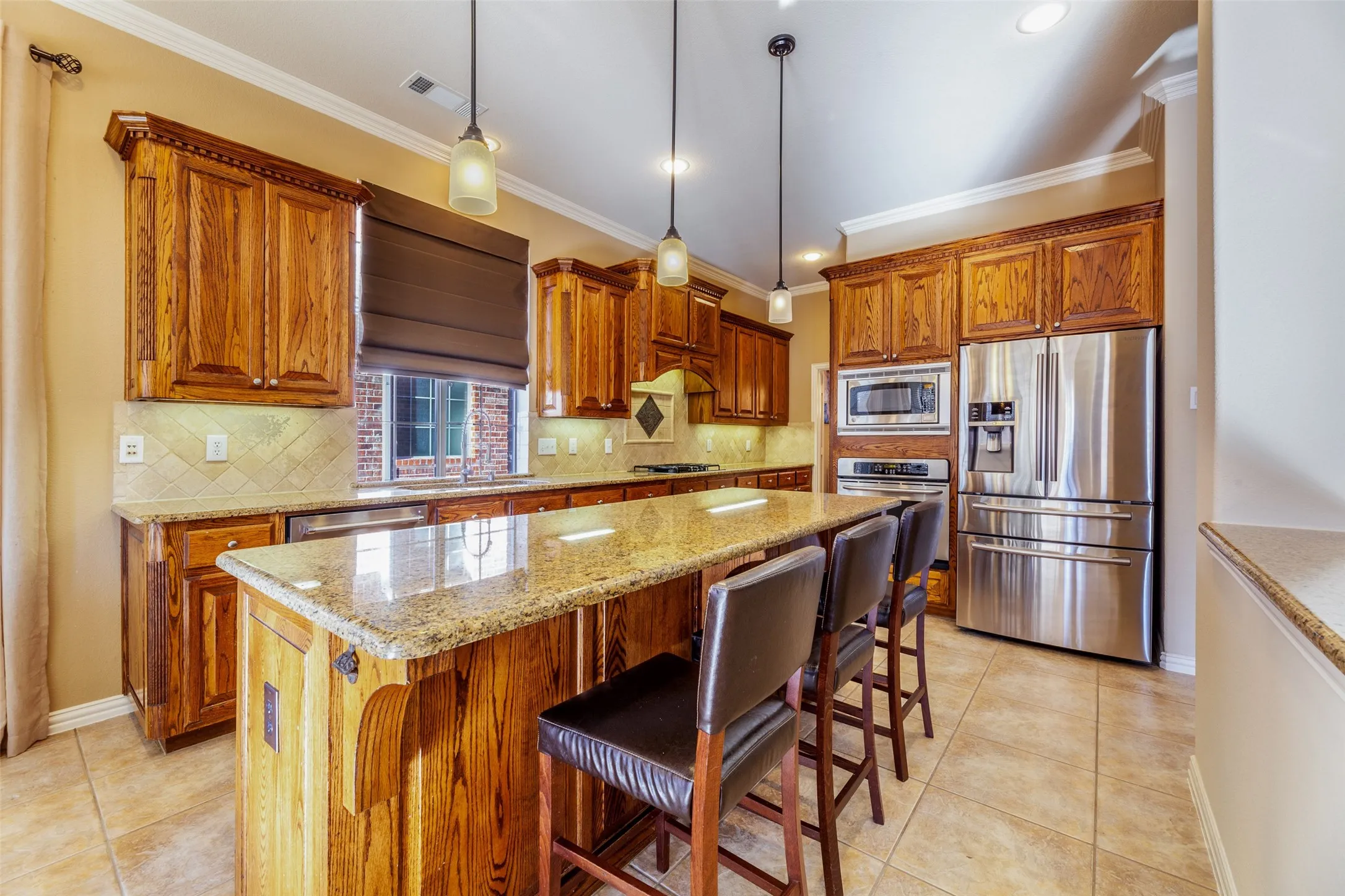 Kitchen featuring a sink, brown cabinetry, crown molding, a center island, and appliances with stainless steel finishes