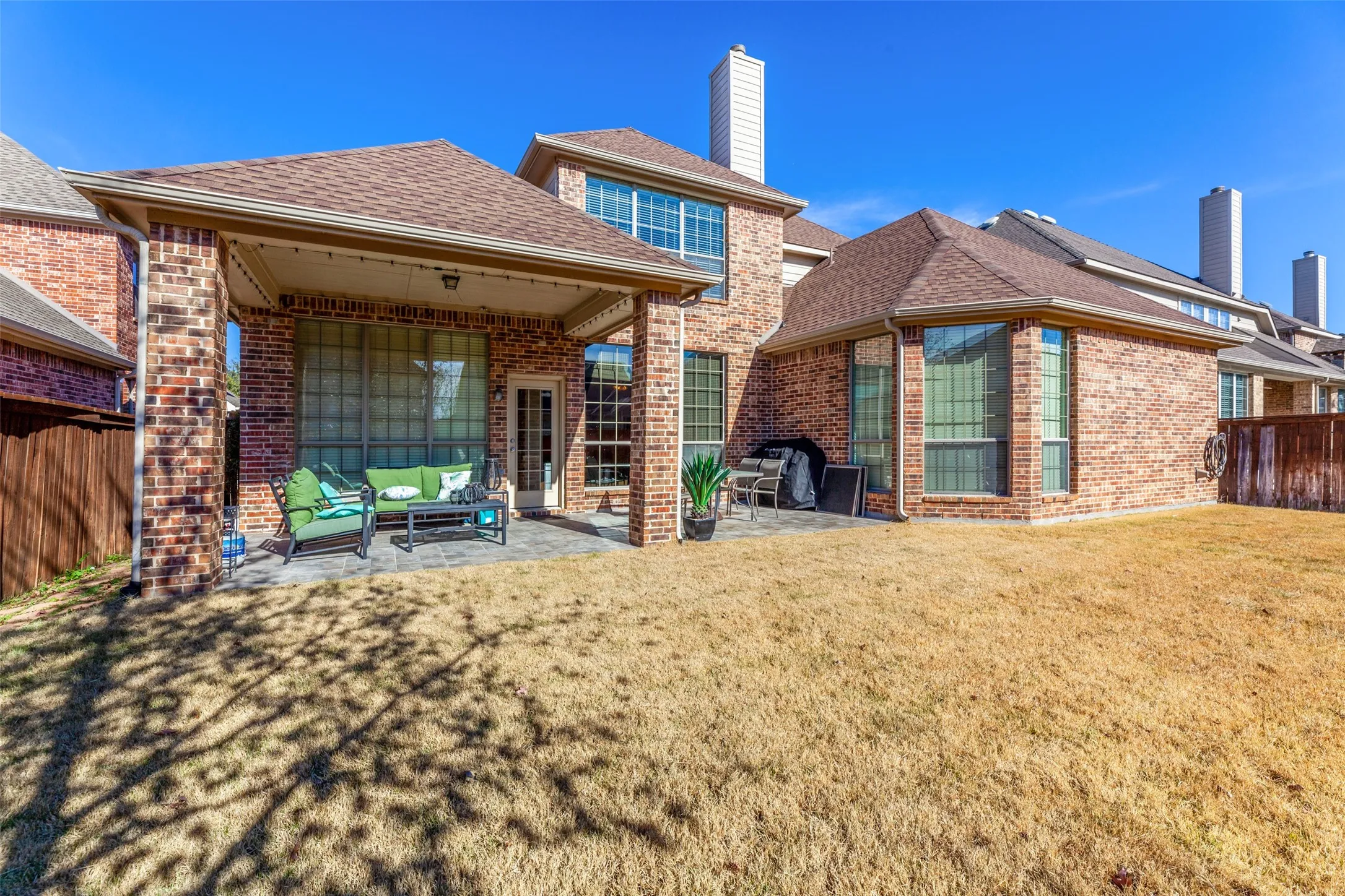 Rear view of house with fence, an outdoor living space, a yard, brick siding, and a patio area