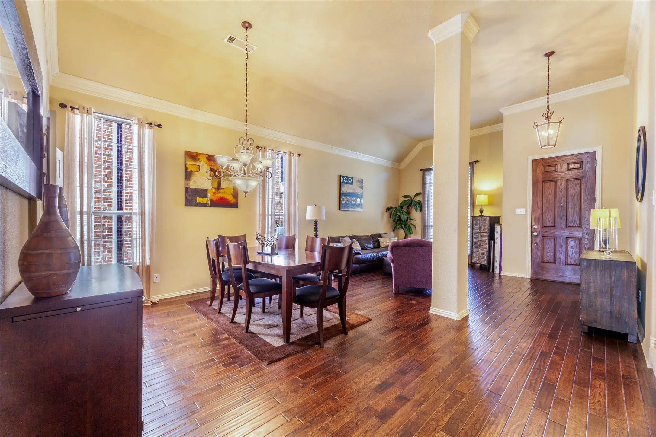 Dining space featuring baseboards, a chandelier, lofted ceiling, ornamental molding, and dark wood-style floors