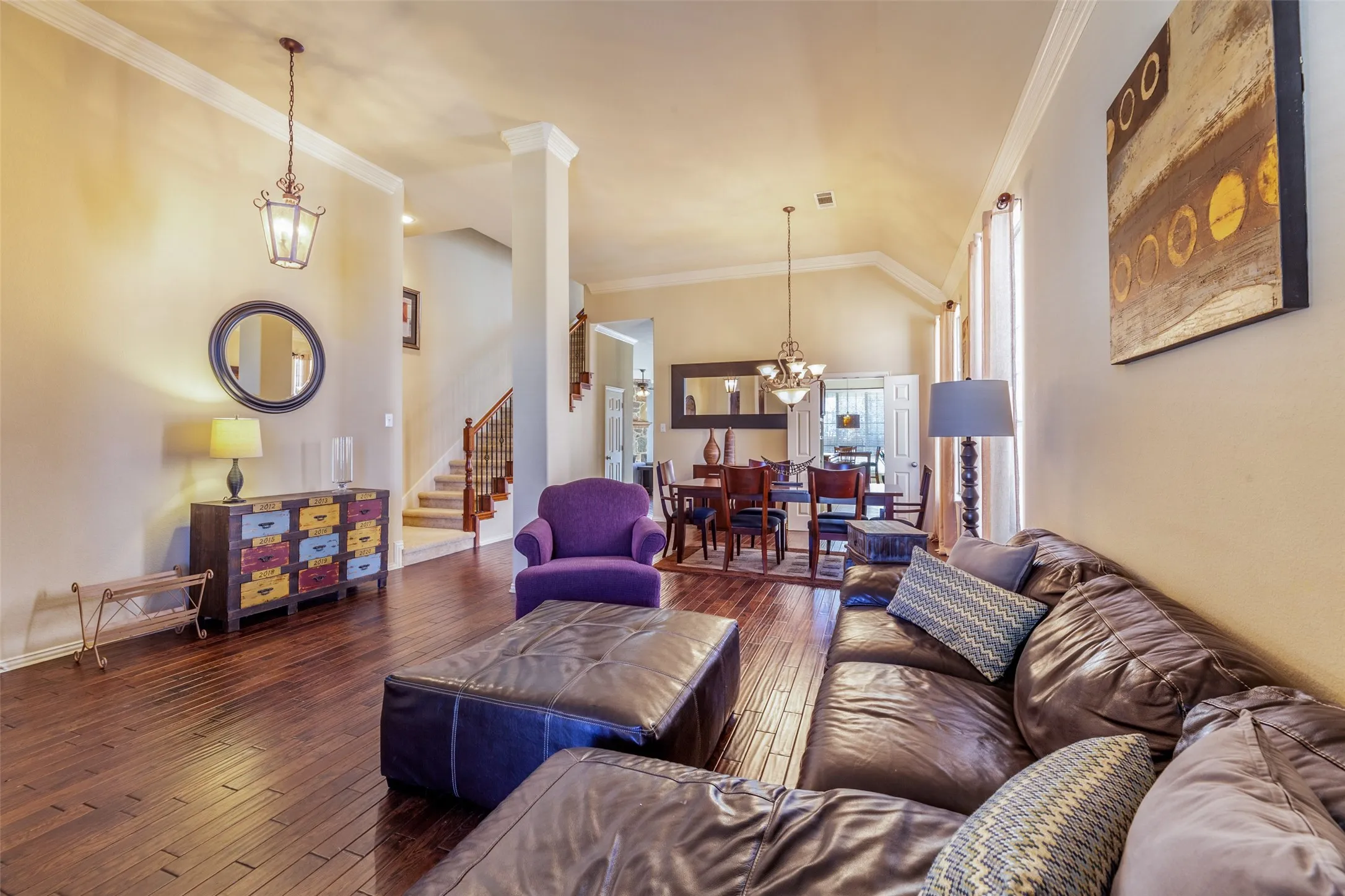 Living area with stairs, hardwood / wood-style floors, vaulted ceiling, a chandelier, and crown molding