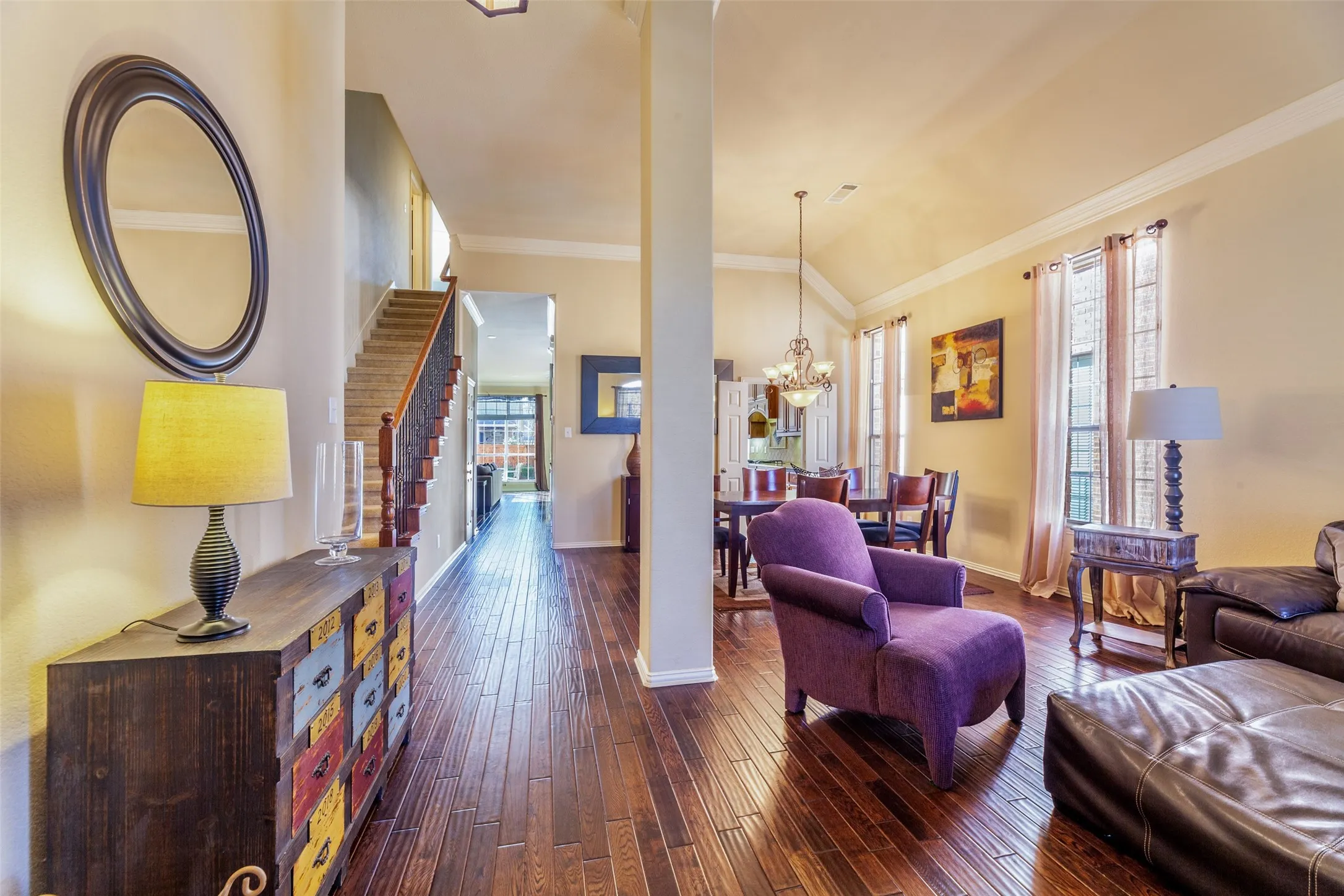 Living room featuring a notable chandelier, baseboards, ornamental molding, dark wood finished floors, and visible vents