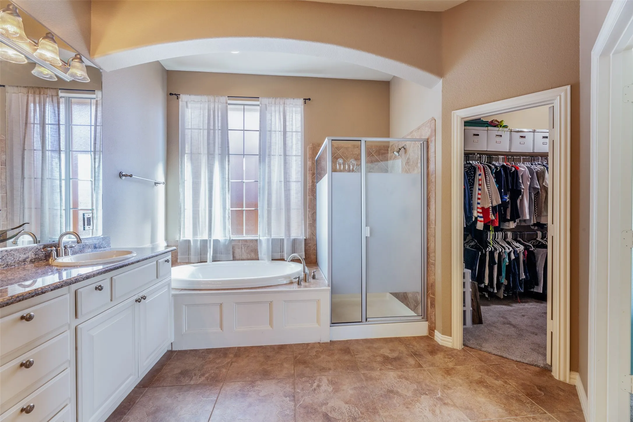 Bathroom with a stall shower, a garden tub, vanity, tile patterned floors, and a spacious closet