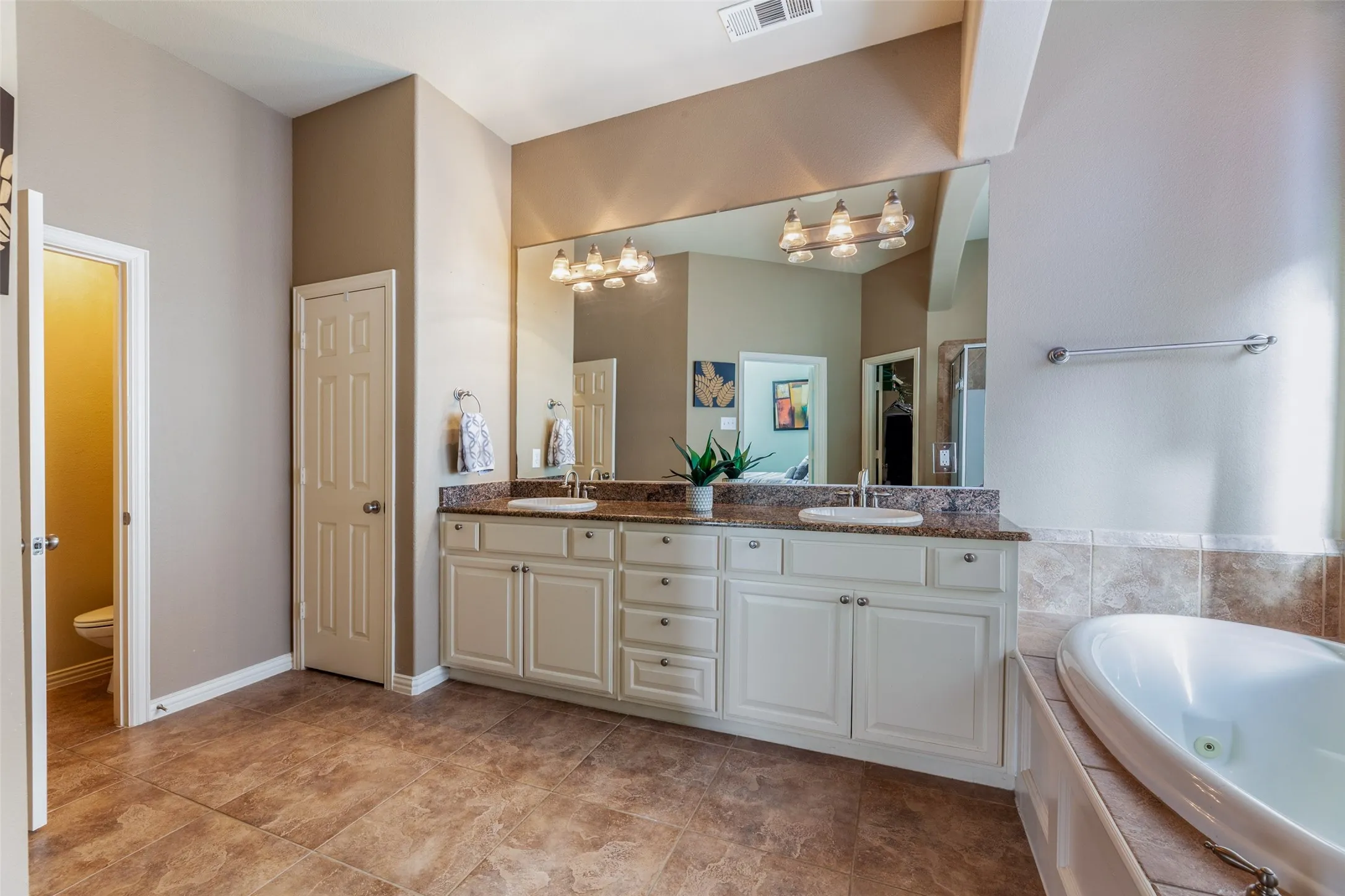 Bathroom with a sink, double vanity, visible vents, and an inviting chandelier