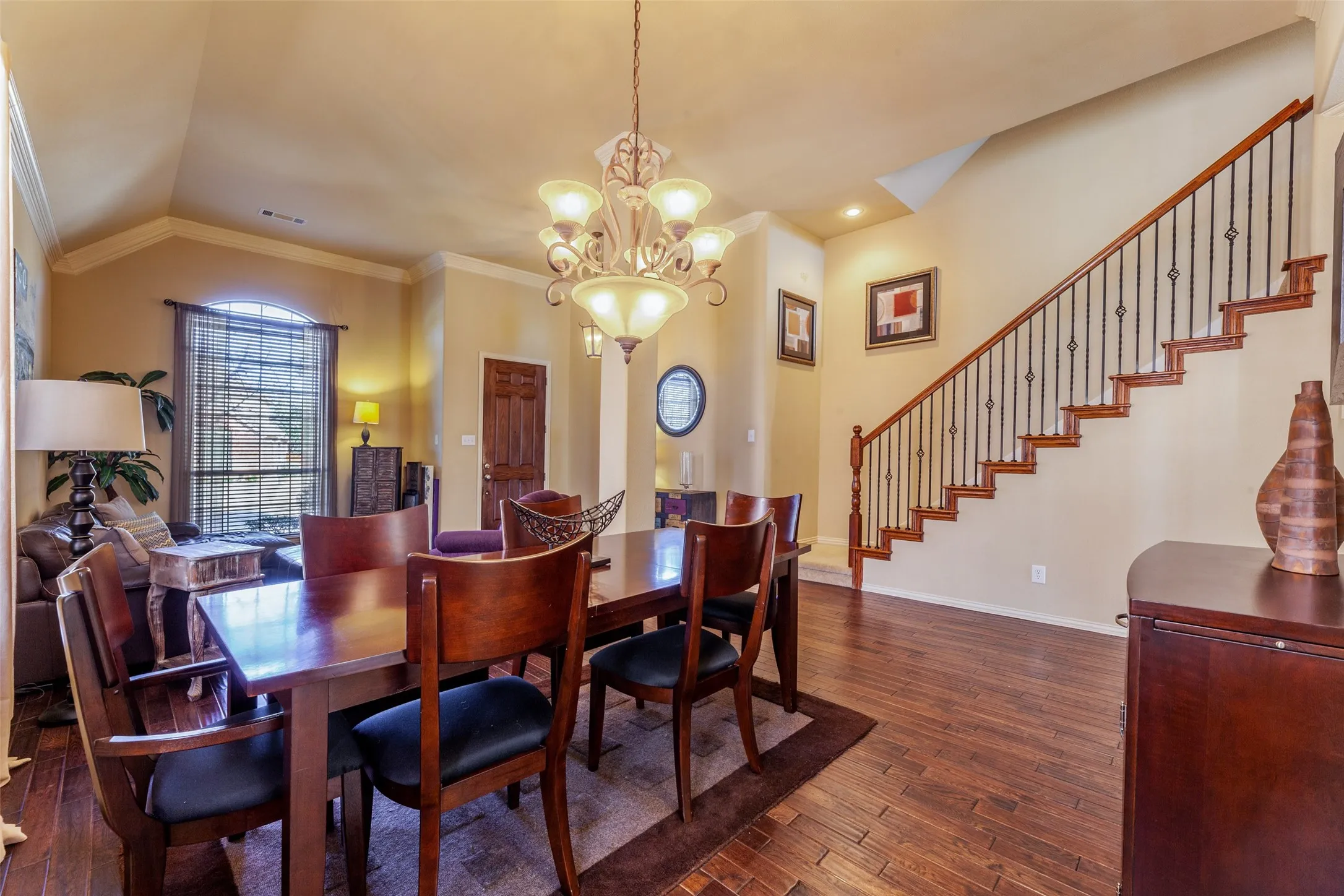 Dining area with baseboards, dark wood-type flooring, a chandelier, crown molding, and vaulted ceiling