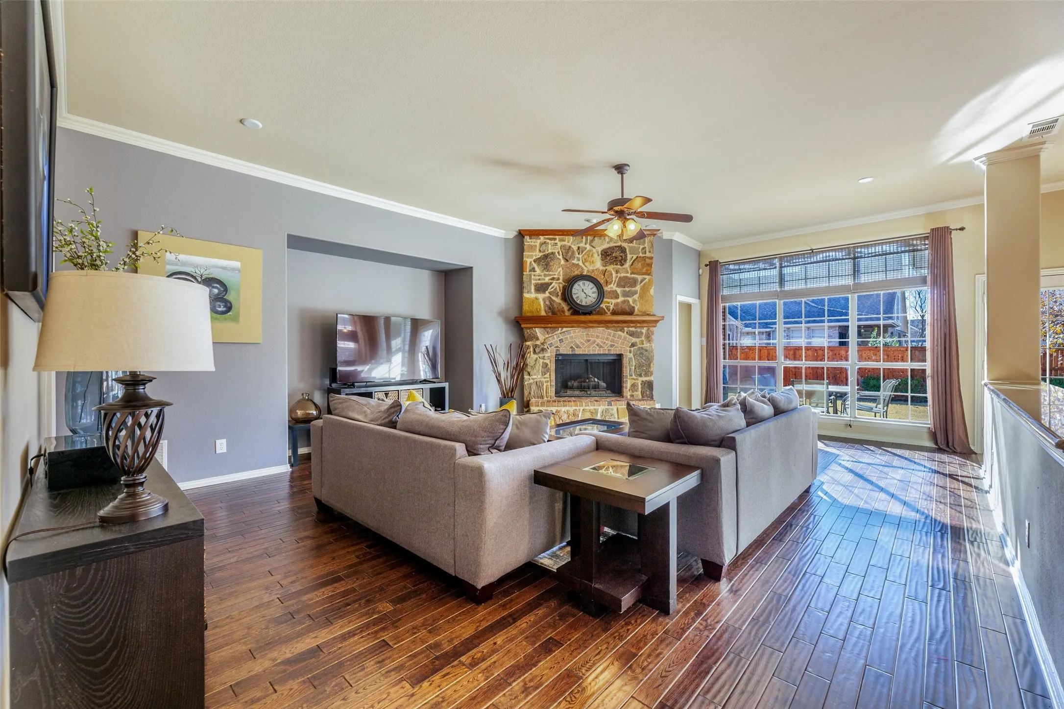 Living area with crown molding, dark wood finished floors, a fireplace, and a ceiling fan