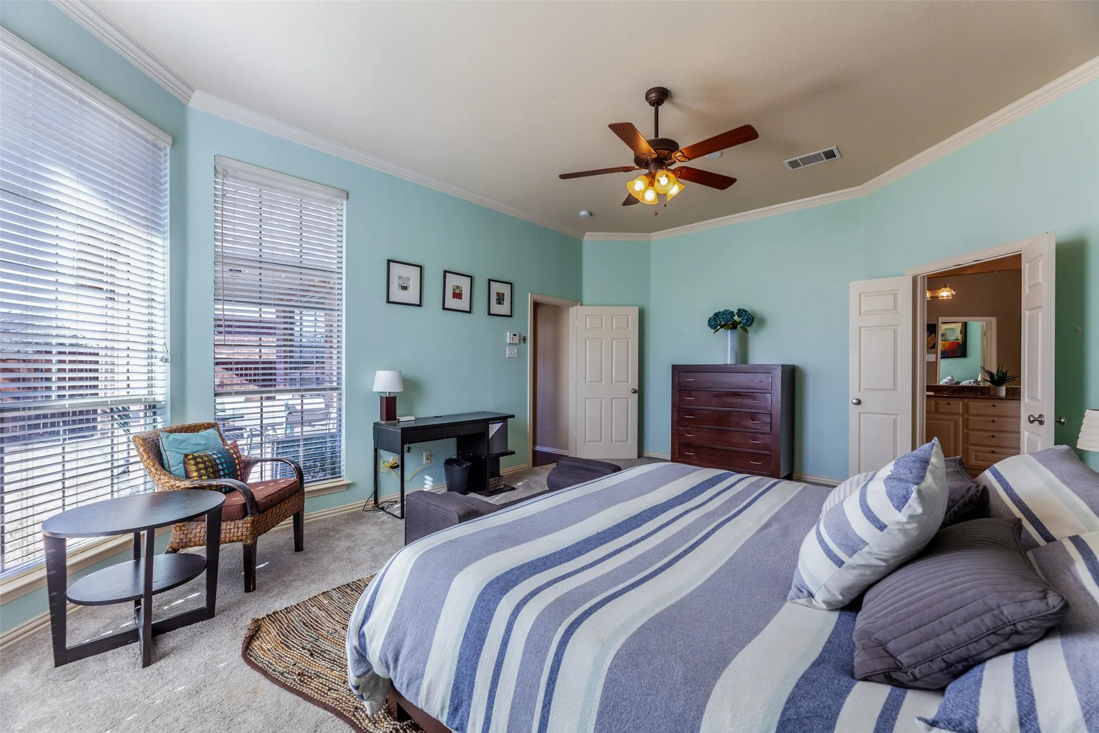Bedroom with light colored carpet, crown molding, visible vents, and multiple windows