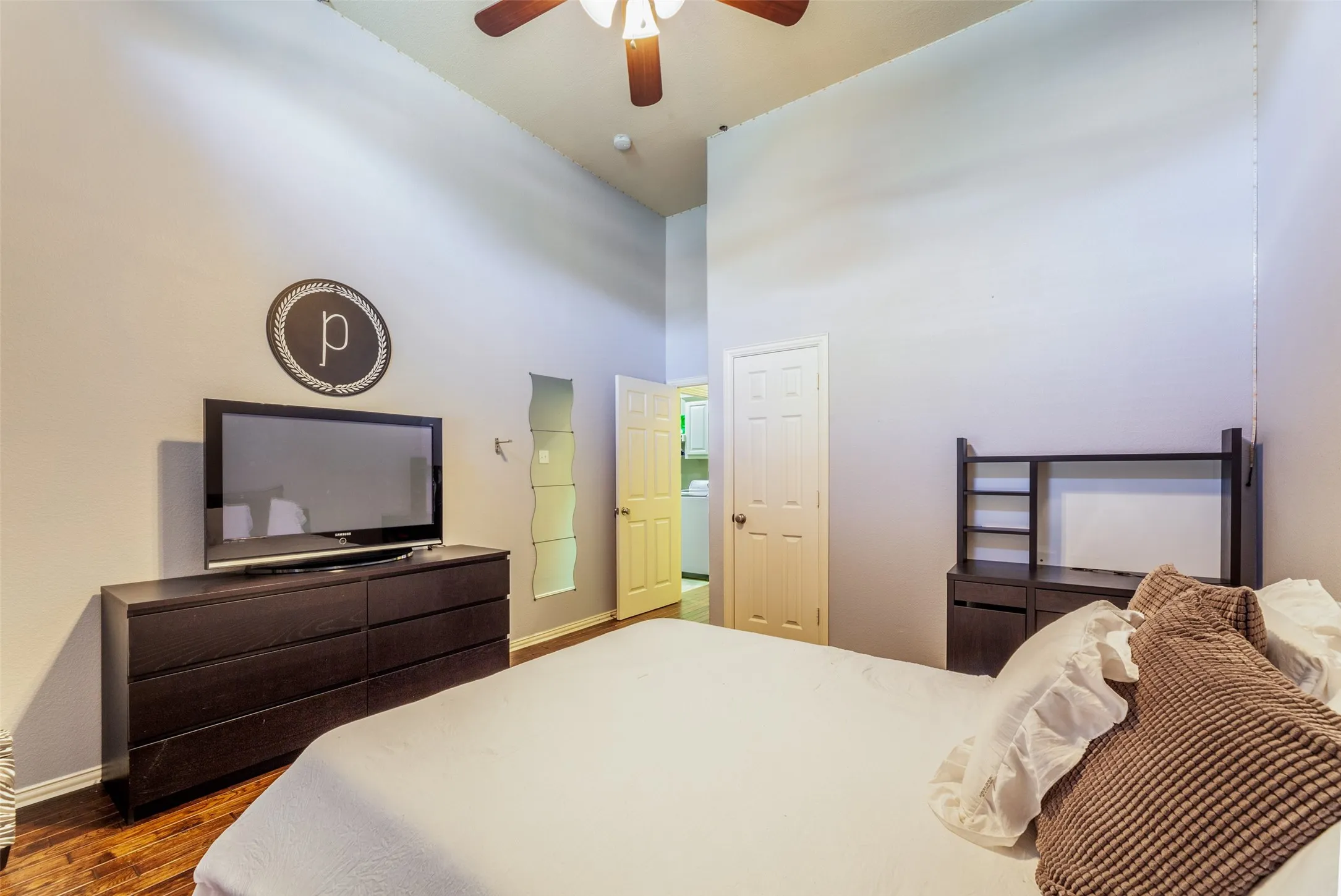 Bedroom featuring baseboards, a ceiling fan, a high ceiling, and wood finished floors