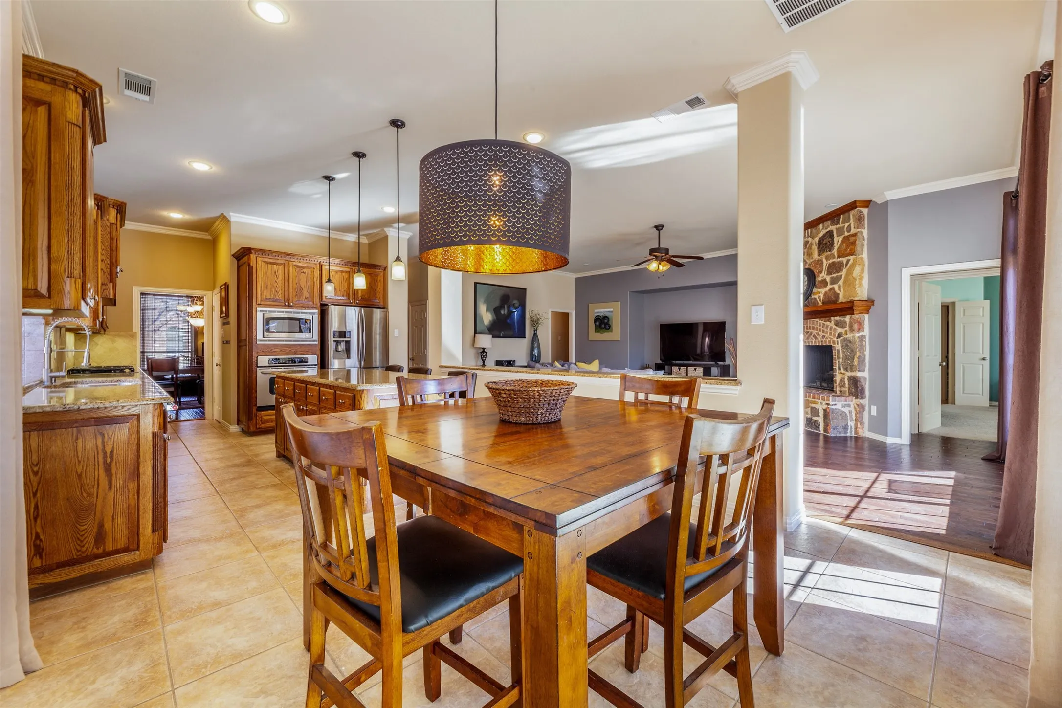 Dining space with ceiling fan, ornamental molding, light tile patterned floors, and visible vents