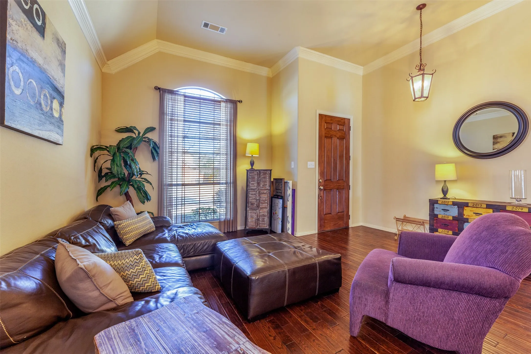 Living area featuring baseboards, ornamental molding, visible vents, and wood finished floors