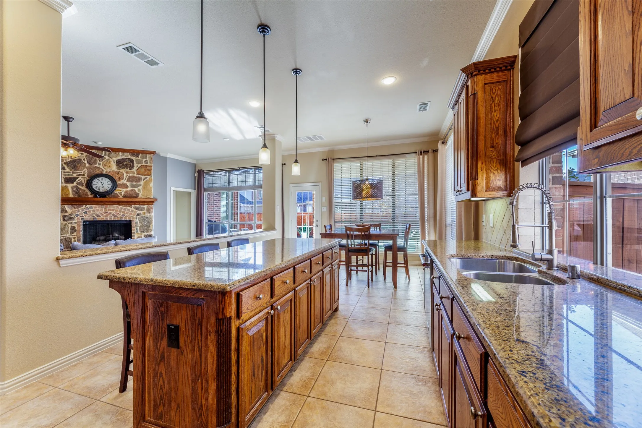 Kitchen featuring ornamental molding, ceiling fan, visible vents, a sink, and brown cabinets