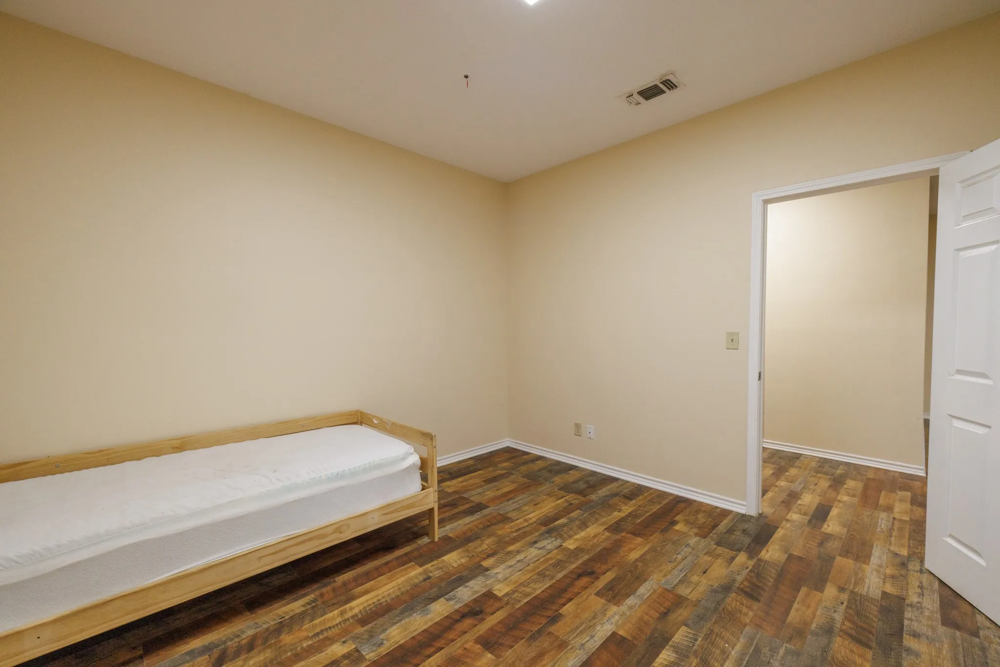 Wood-finish flooring, neutral wall tones, white trim, and a doorway opening