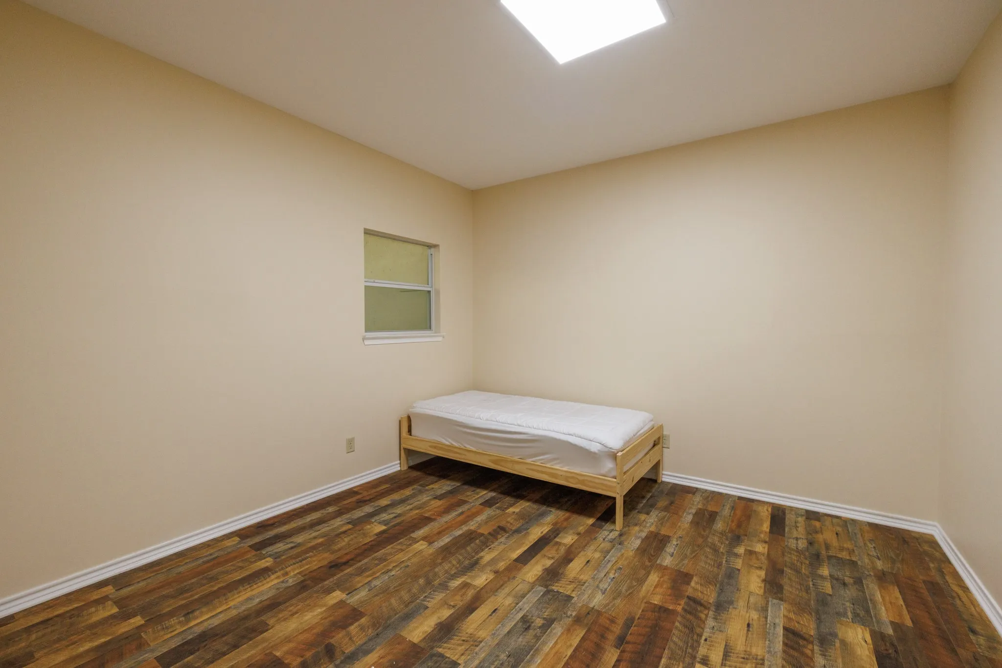 Recycled wood-finish flooring, neutral wall paint, and a recessed ceiling light fixture
