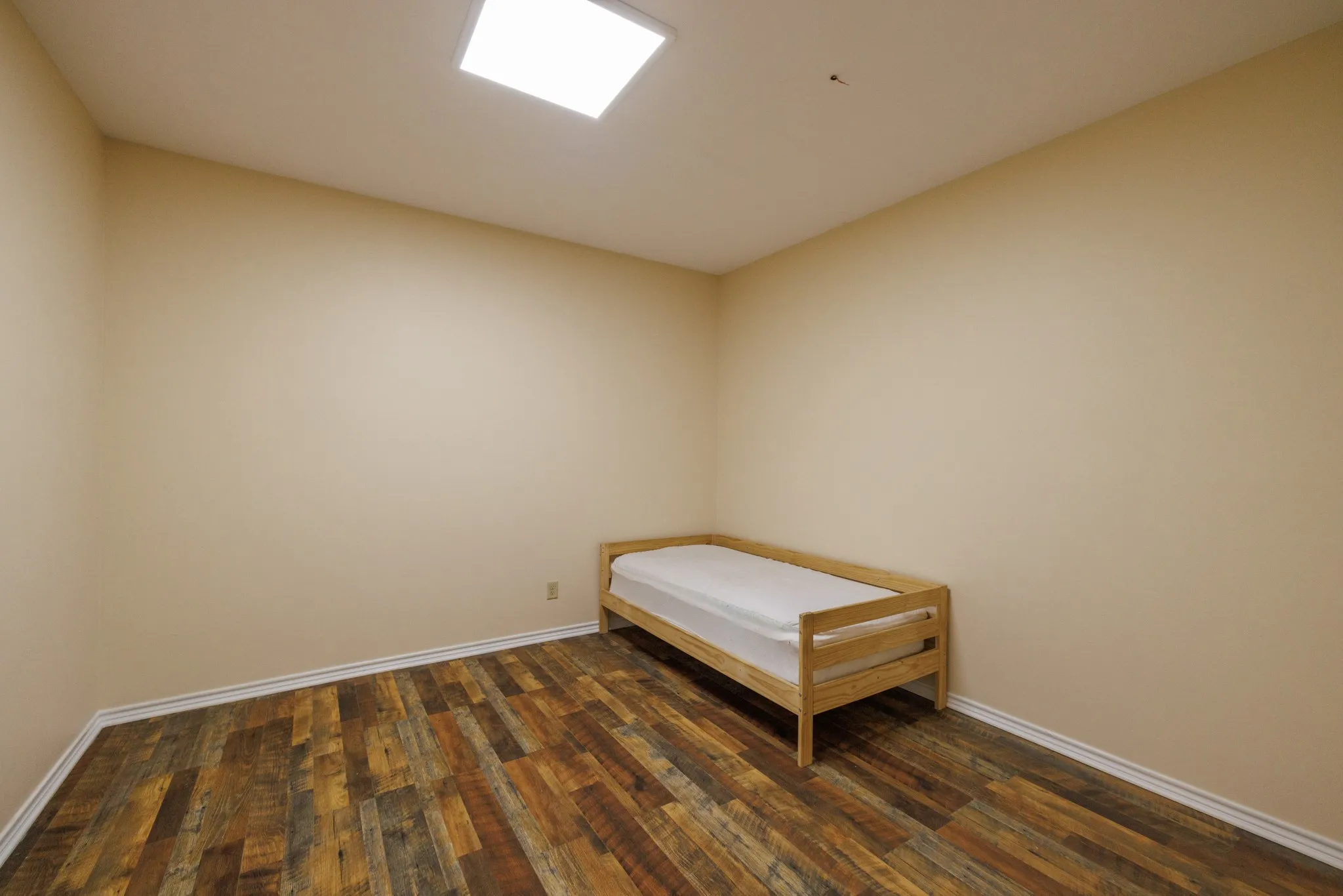 Recessed lighting illuminates the room, featuring wood-finish flooring and light-toned walls