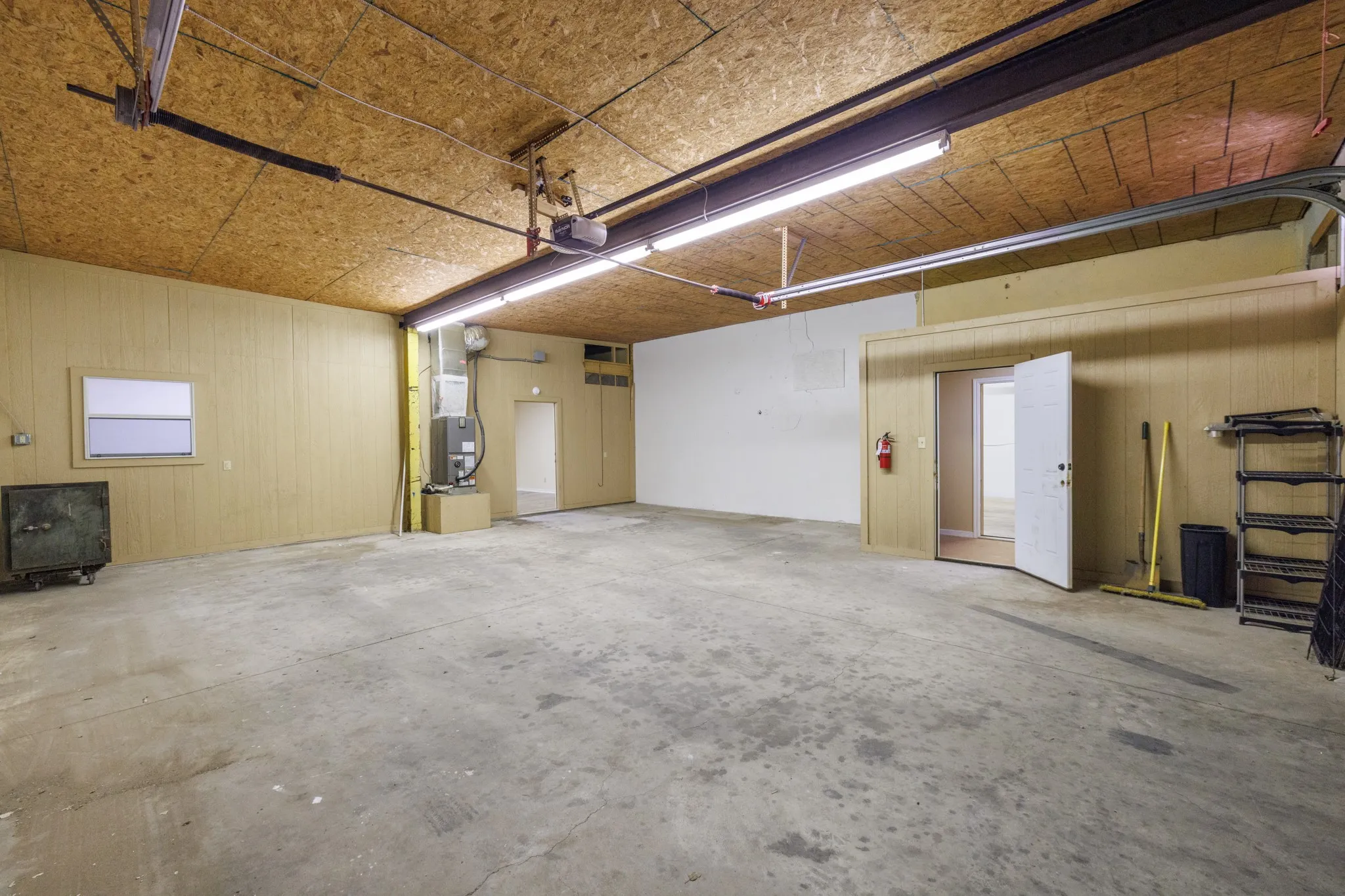 Expansive interior space with concrete flooring, panel walls, and exposed ceiling joists
