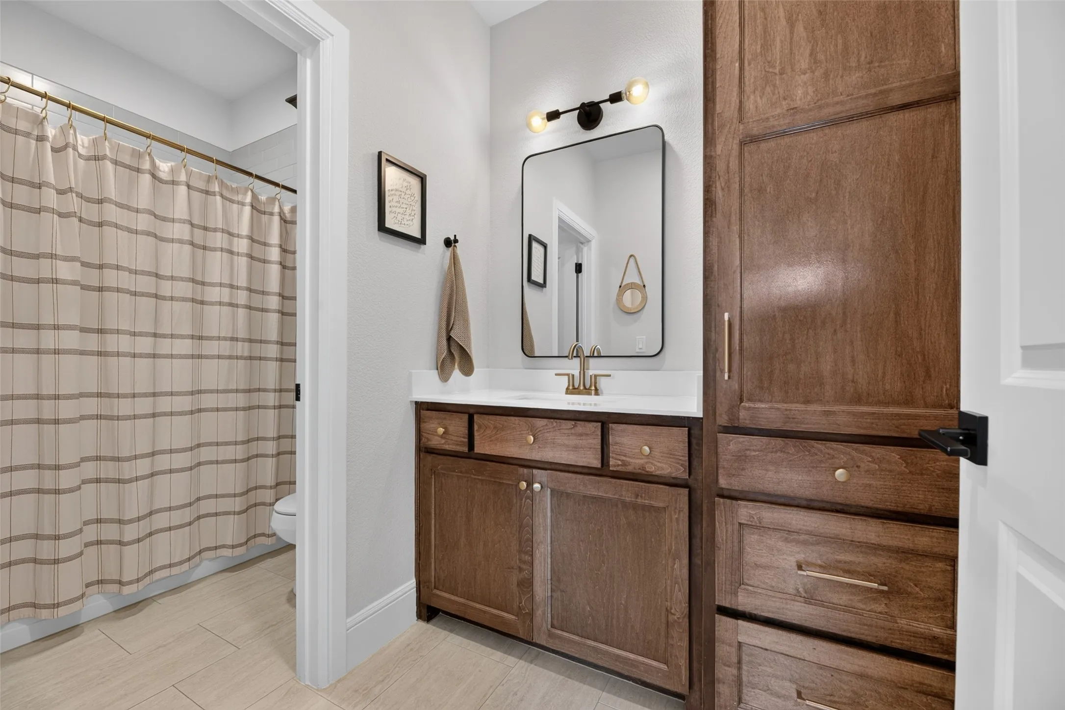 Wood-finish vanity with a white countertop and gold-tone faucet
