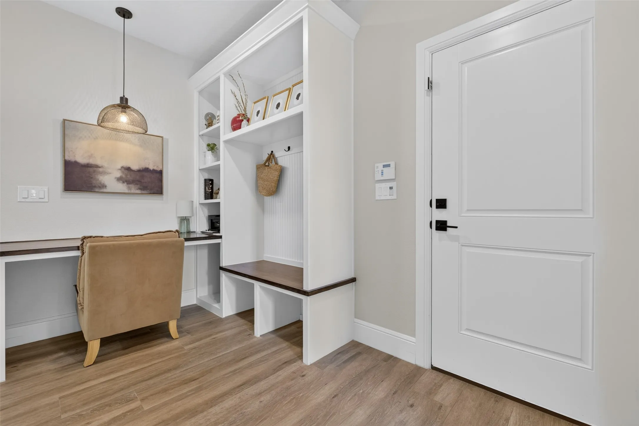 Built-in desk area, integrated shelving, wood-finish flooring, built-in bench seating, and a panel door with matte black hardware