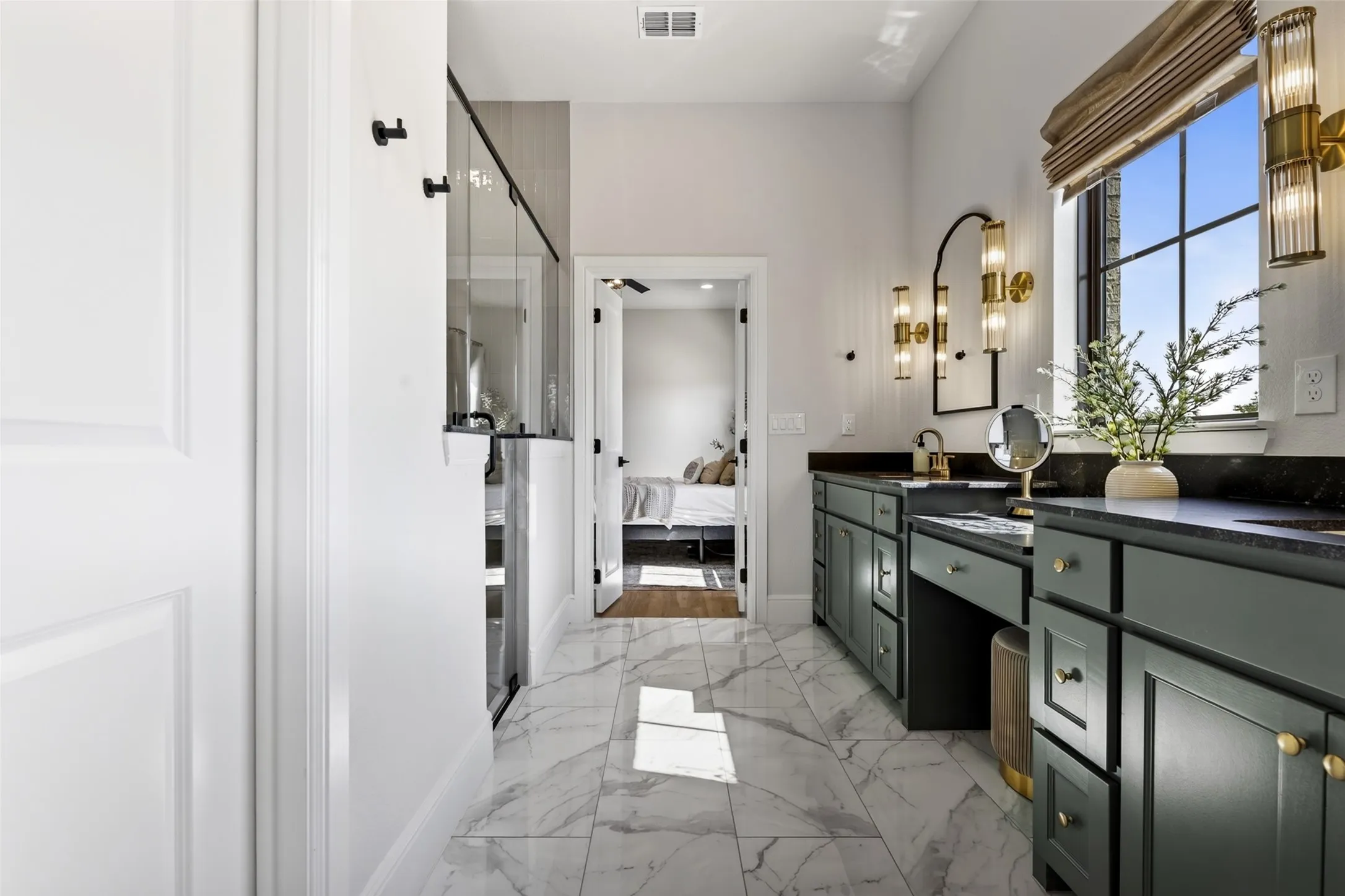 Spacious bathroom featuring marble-finish flooring, dual vanity with dark cabinetry, dark countertops, and a large window with natural light