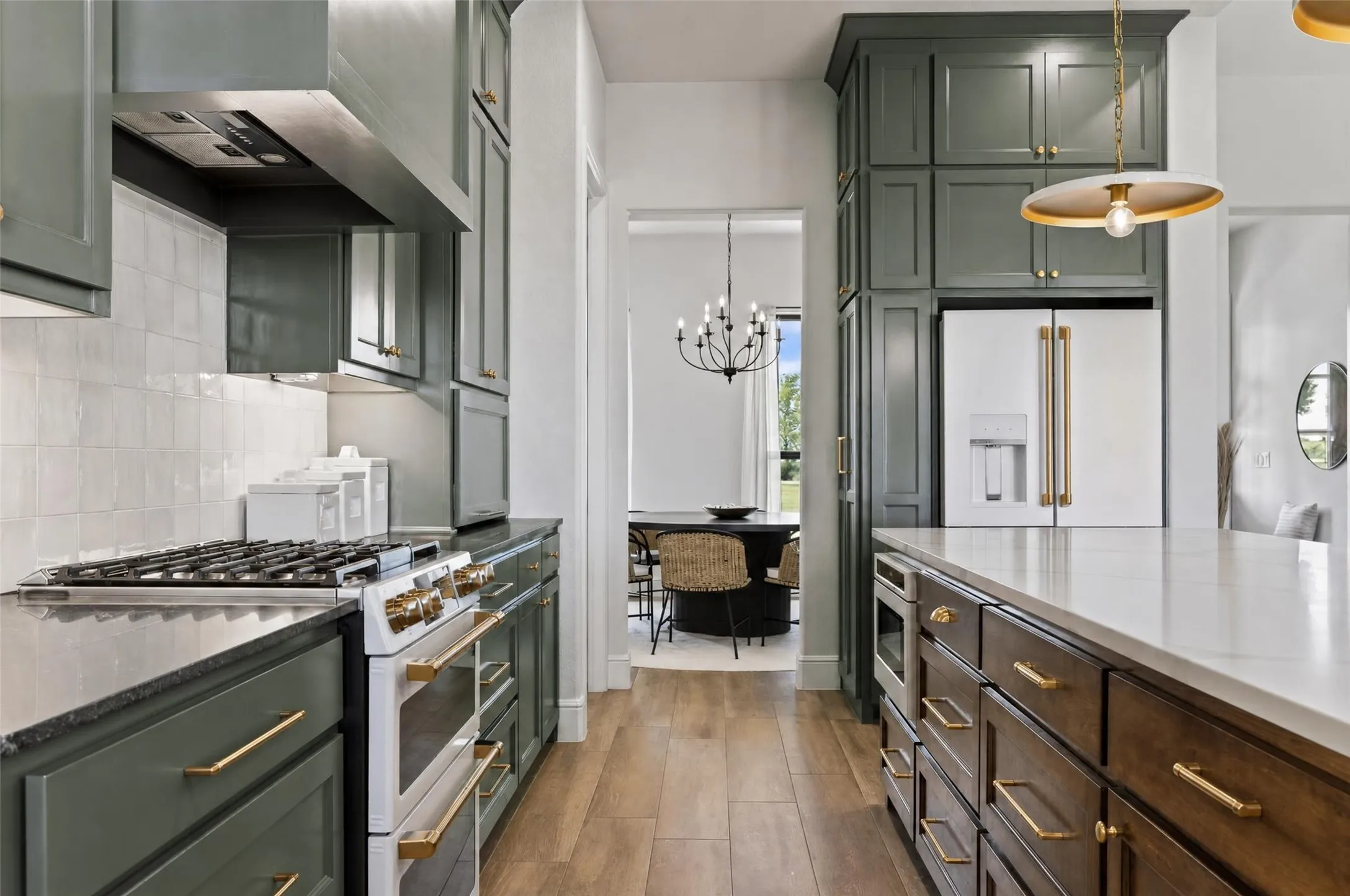 Spacious kitchen featuring wood-finish flooring, two-tone cabinetry, a large kitchen island with integrated microwave, and a wall-mounted range hood