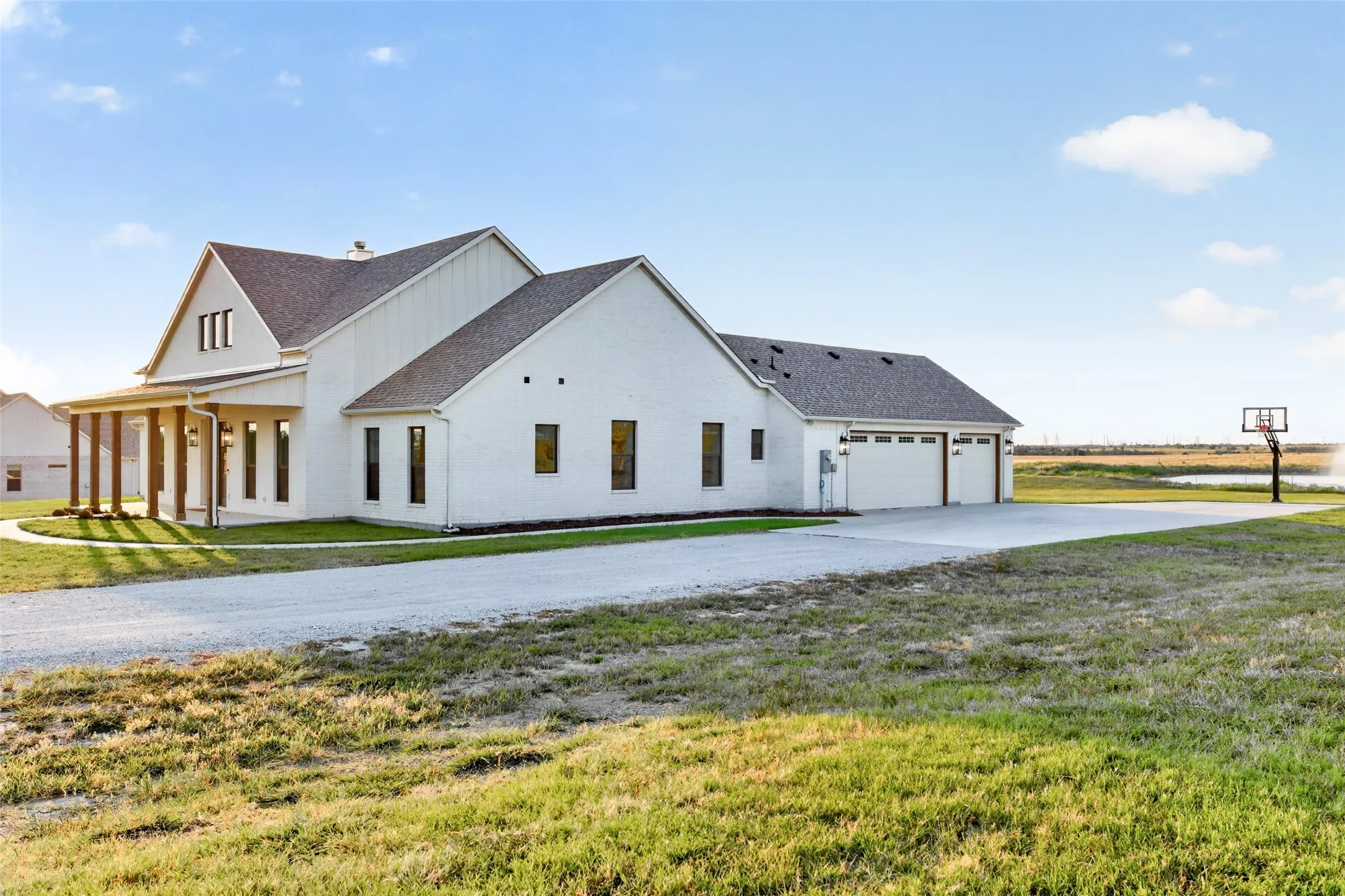 Modern farmhouse architectural style featuring a covered porch with substantial wood columns, a multi-car garage, and a concrete driveway