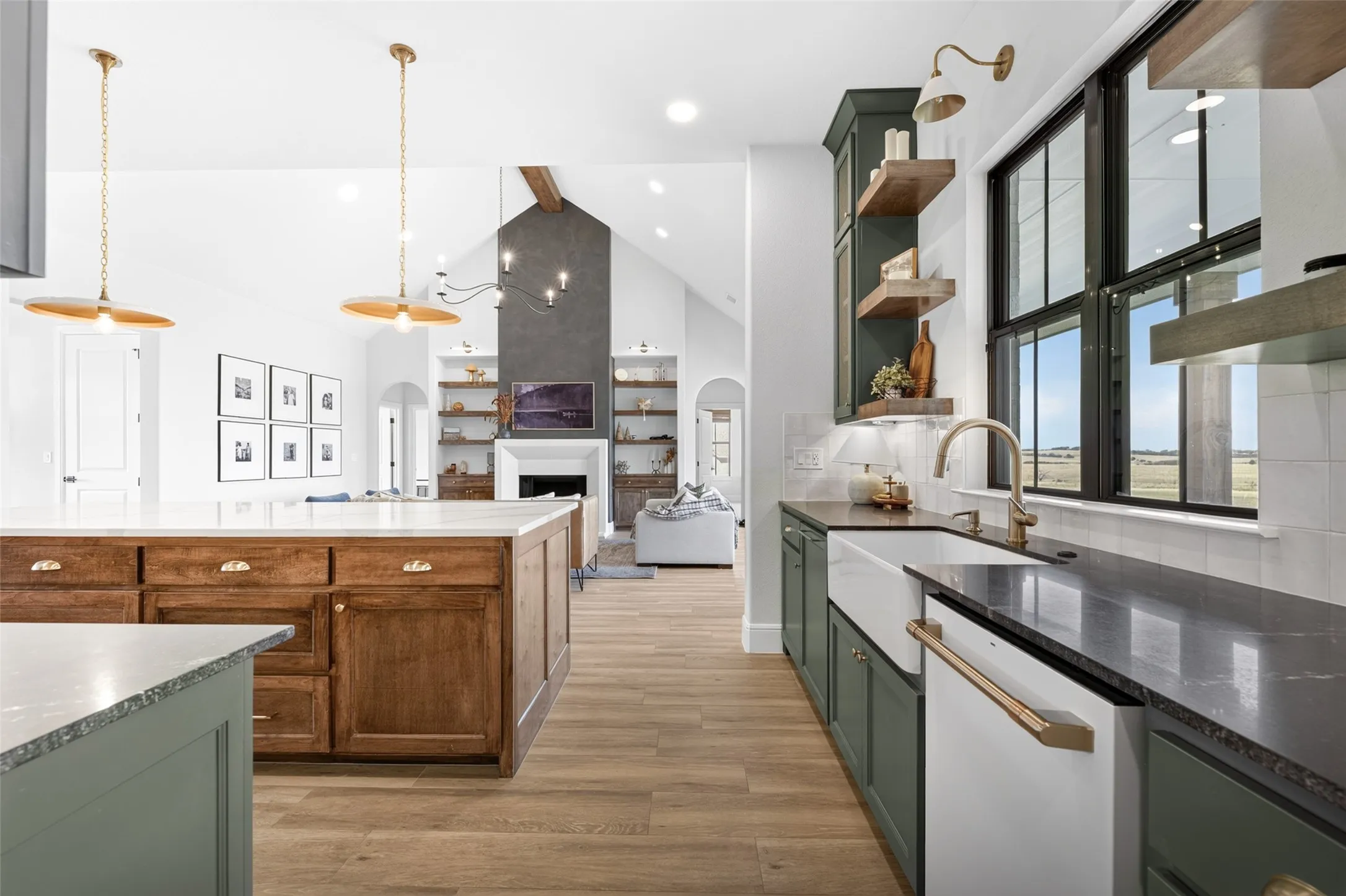 Open-concept kitchen featuring an oversized island, wood-finish flooring, two-tone cabinetry, a farmhouse sink, and a high vaulted ceiling