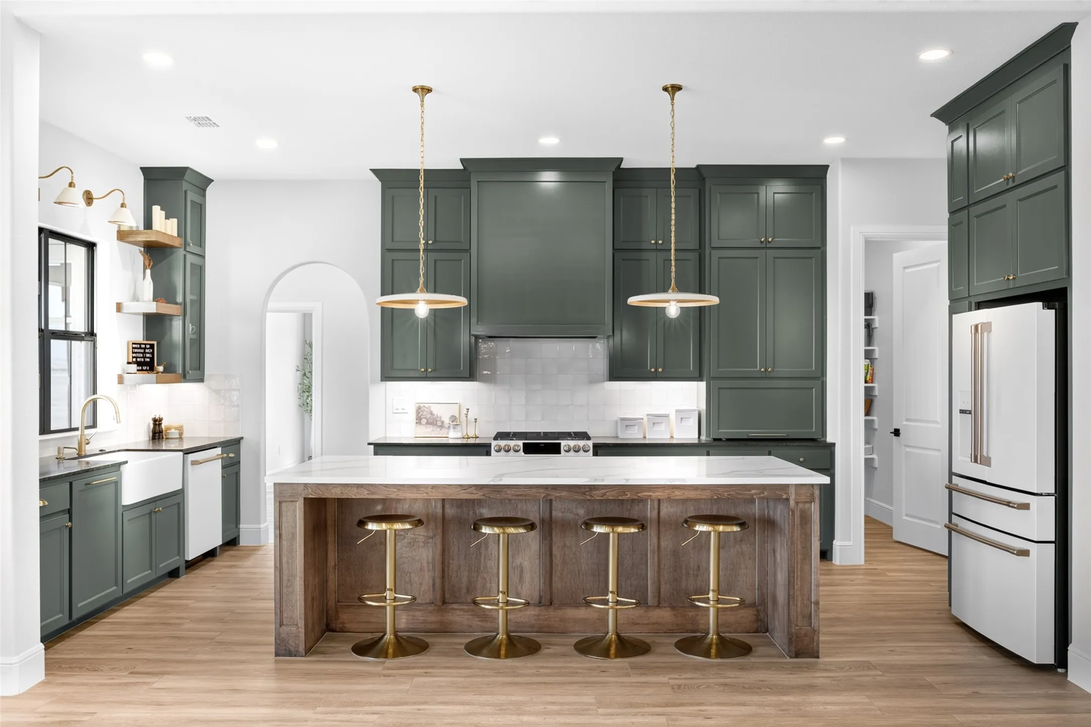 Kitchen featuring olive-toned cabinetry, a wood-finish island with a stone countertop, wood-finish flooring, and a white tile backsplash
