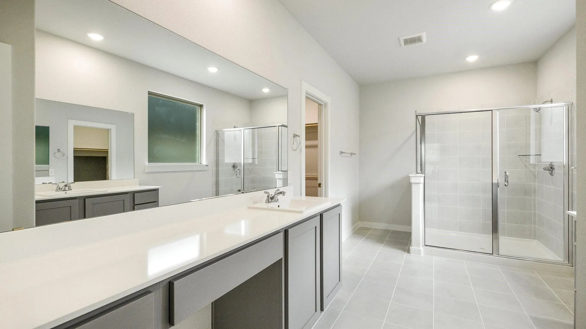 Spa-inspired primary bathroom featuring dual vanities with integrated sinks, quartz countertops, and polished chrome fixtures
