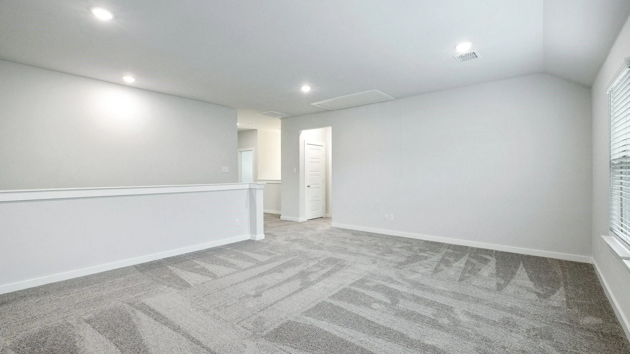 Bright, light-filled room featuring recessed ceiling lighting, neutral white wall finishes with chair rail detailing, and patterned carpet flooring in neutral​​‌​​​​‌​​‌‌​‌‌​​​‌‌​‌​‌​‌​​​‌​​ tones