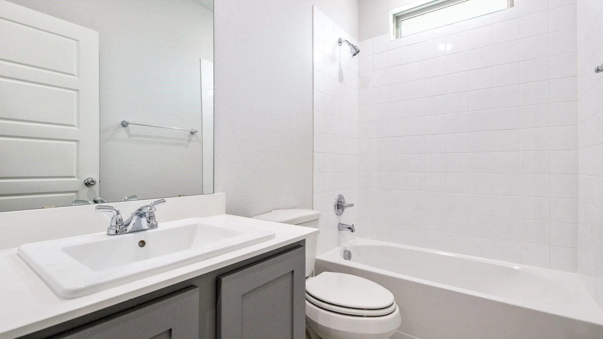 White ceramic tile shower surround with a built-in bathtub, a window, and chrome fixtures