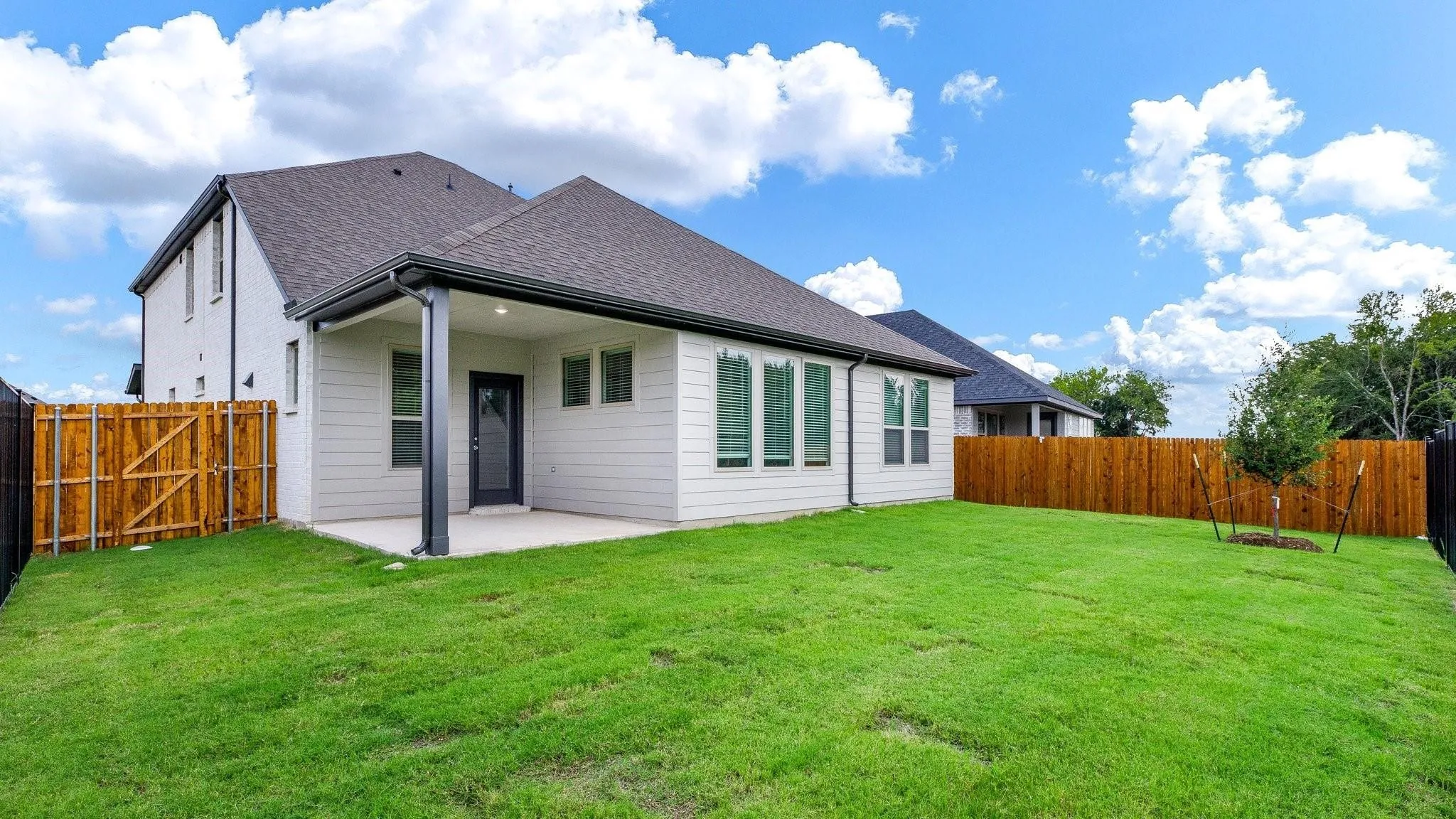 Modern home featuring a clean-lined architectural design with a dark pitched roof, white exterior siding, and expansive glass panels