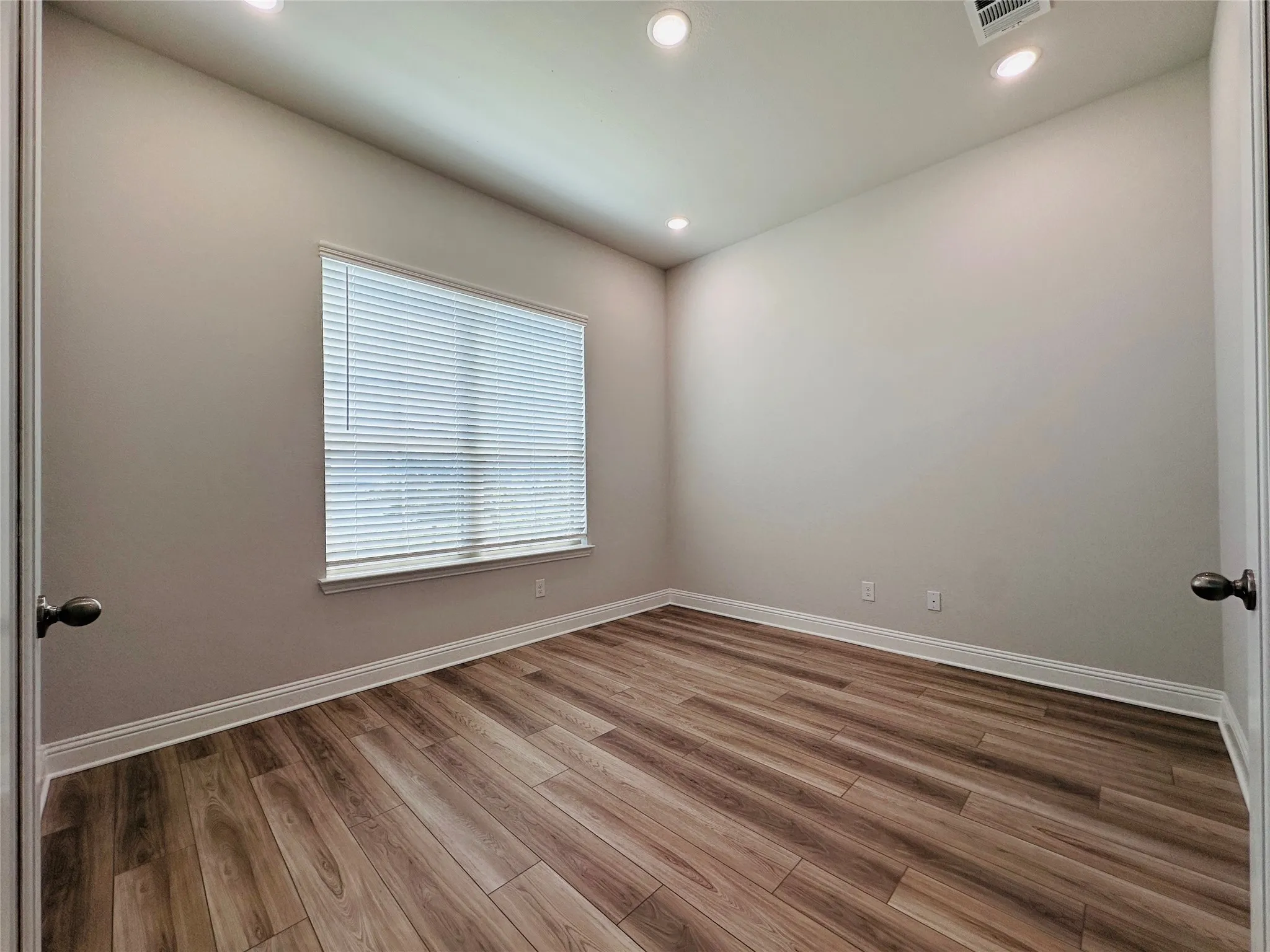 Recessed lighting, wood-finish flooring, white trim, and a window with blinds
