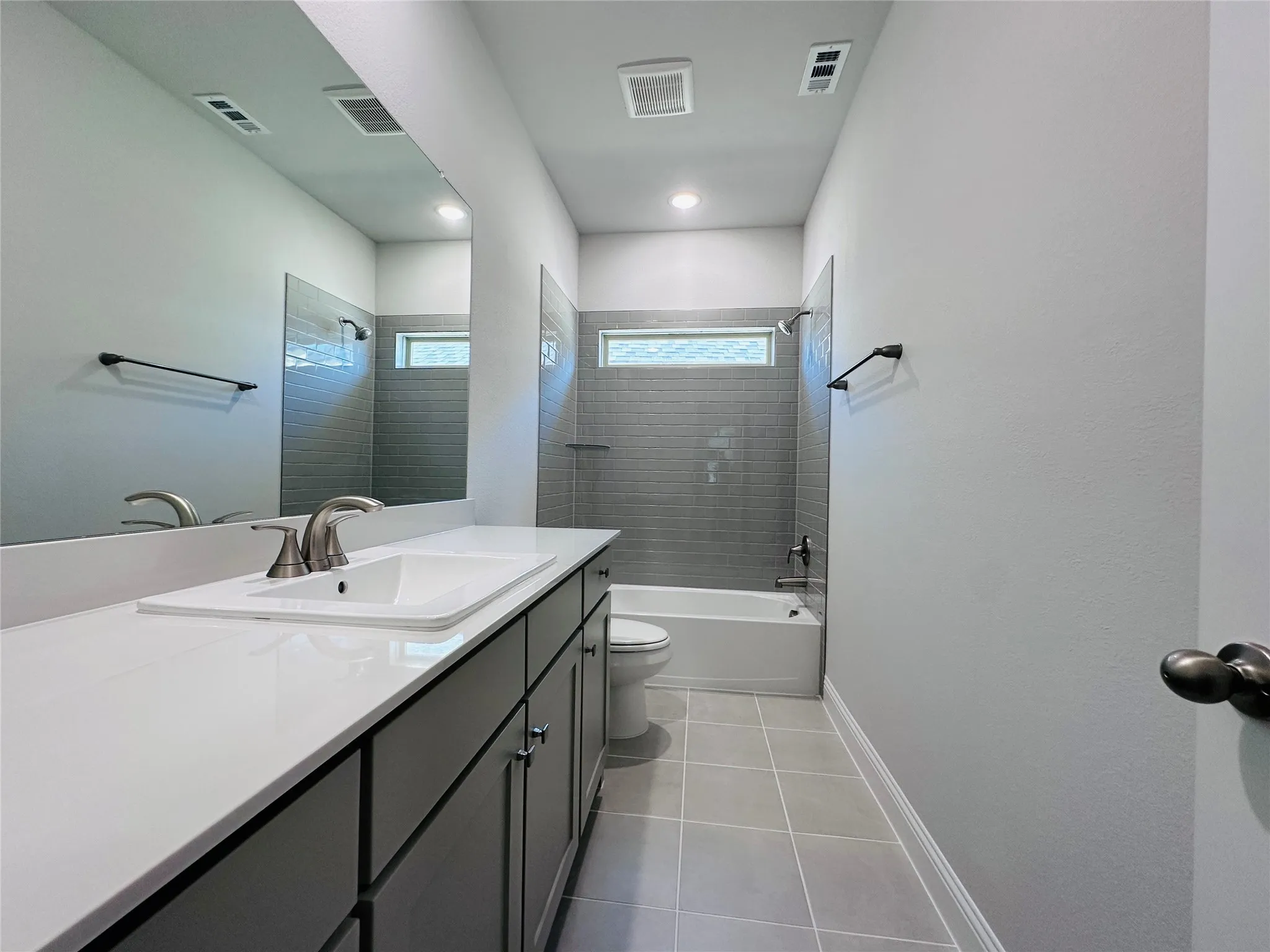 Bathroom featuring a single vanity with stone-finish countertop, undermount sink, and dark cabinetry