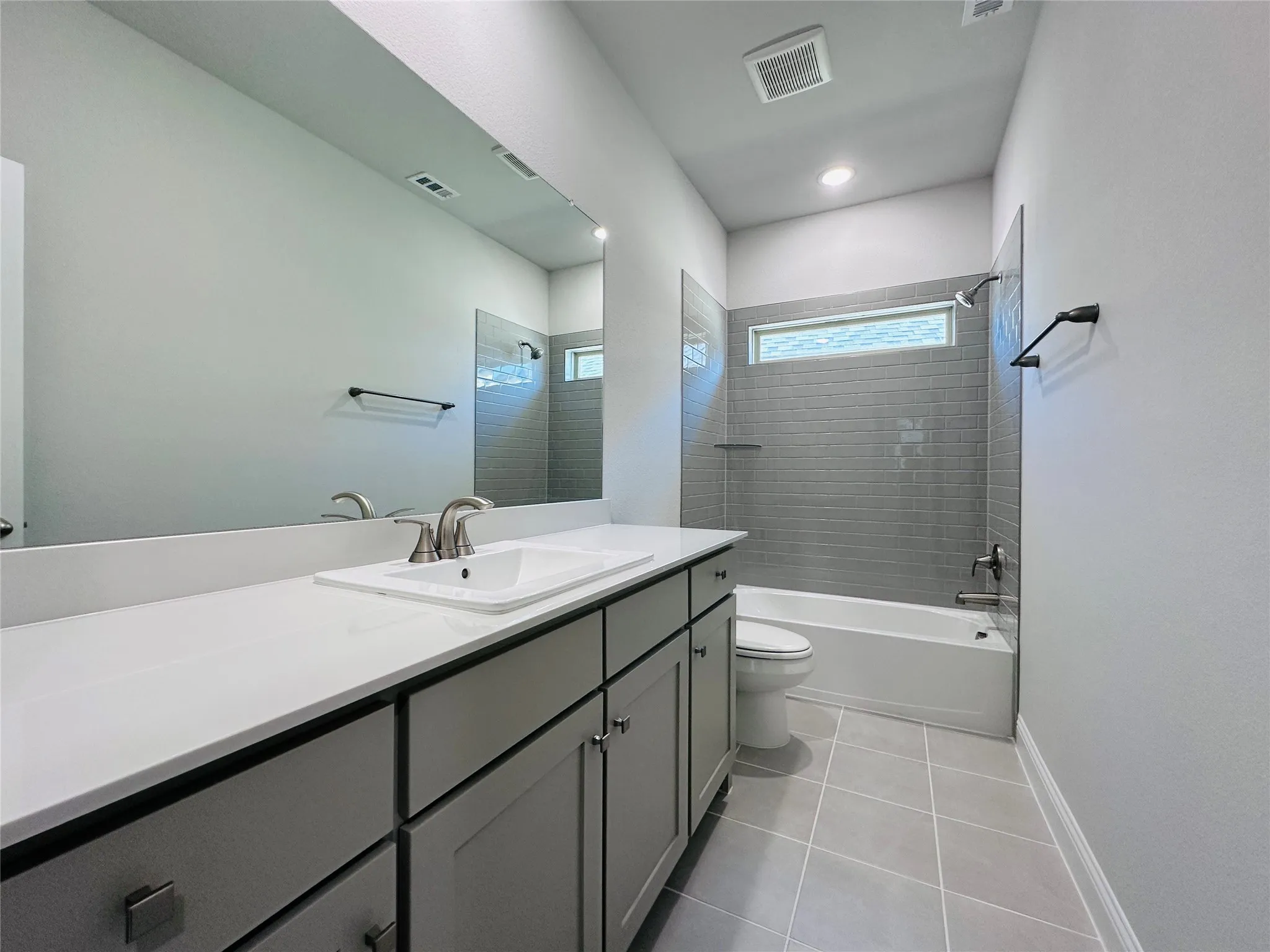 Spa-inspired primary bathroom featuring a double vanity with quartz countertop and matte black hardware, frameless glass-enclosed shower with subway tile surround, soaking tub, and neutral tile flooring throughout