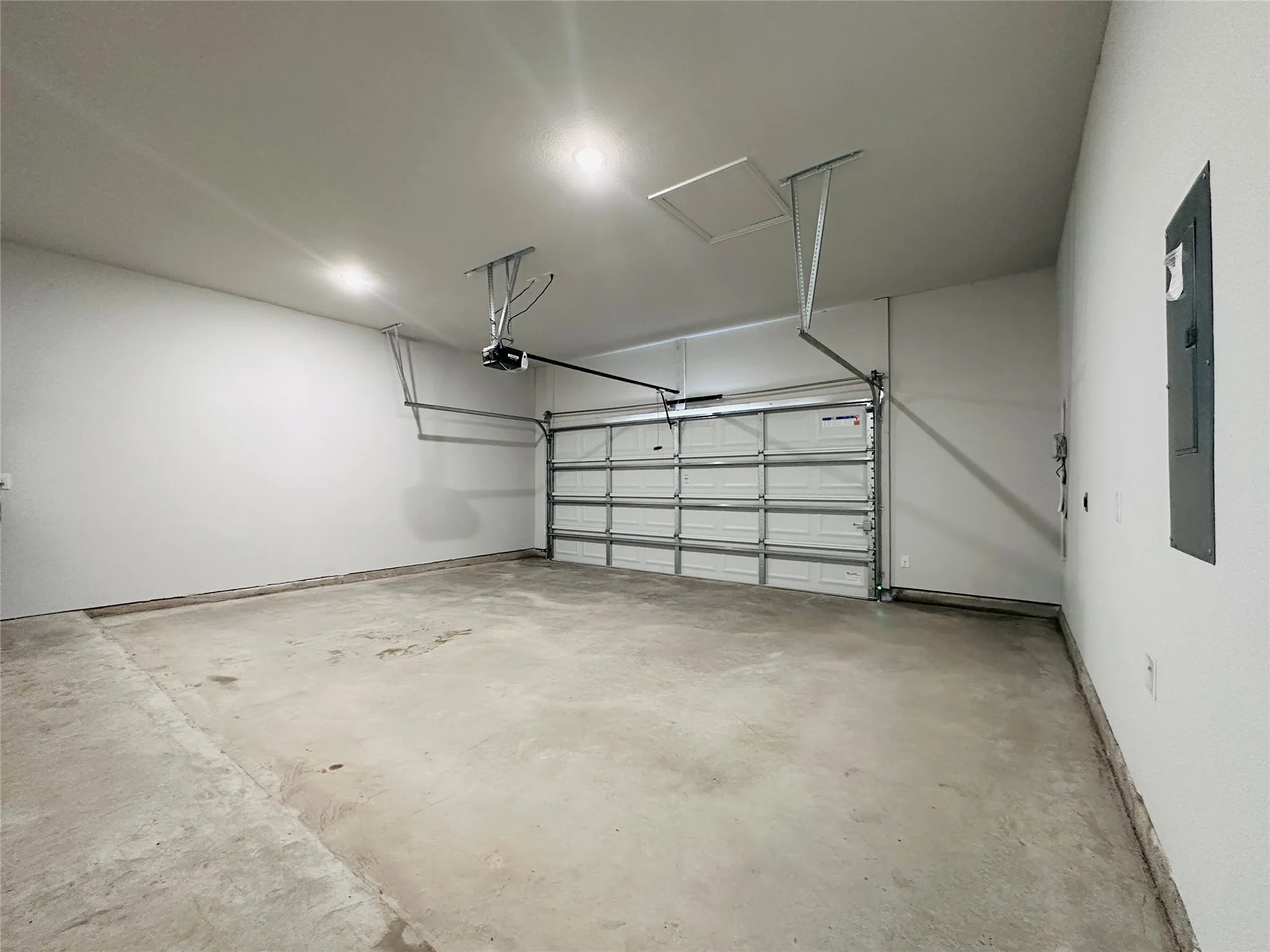 Attached two-car garage featuring a sectional overhead door, automatic opener, and concrete flooring