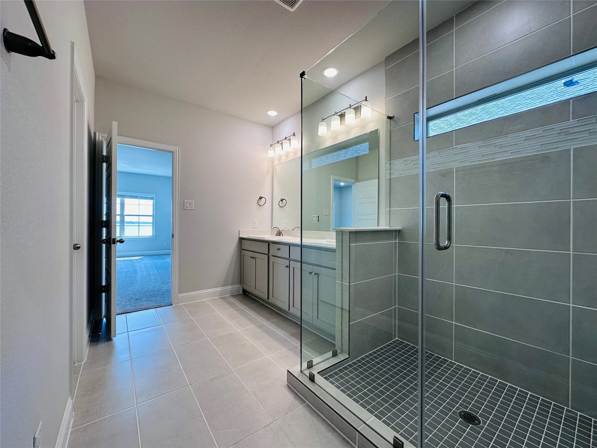Glass-enclosed shower with rectangular tile surround and mosaic accent