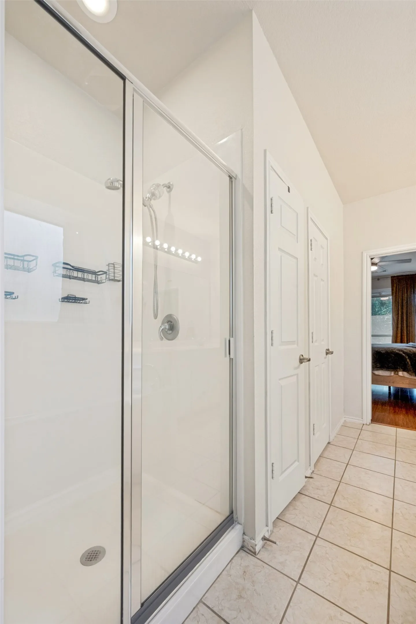 Shower with clear glass enclosure and chrome fixtures, recessed lighting, and tile flooring