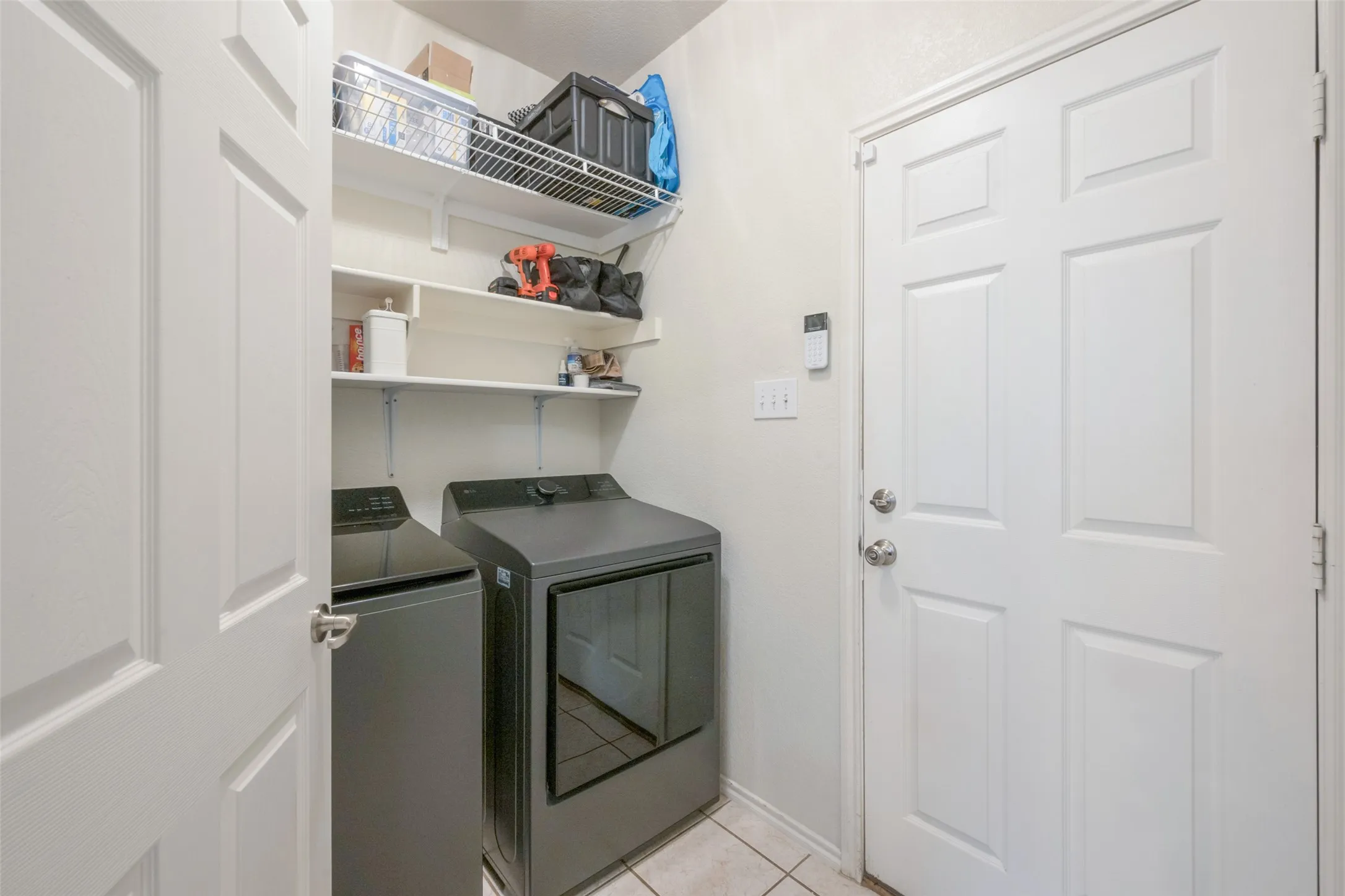 Utility area featuring a top-load washer, front-load dryer, and wall-mounted shelving units