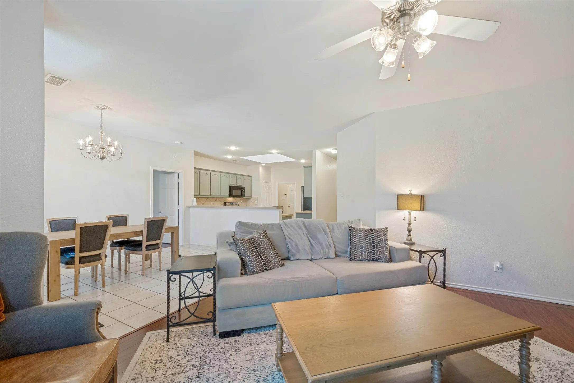 Vaulted ceilings with a ceiling fan, wood-finish flooring, and a kitchen pass-through with recessed lighting
