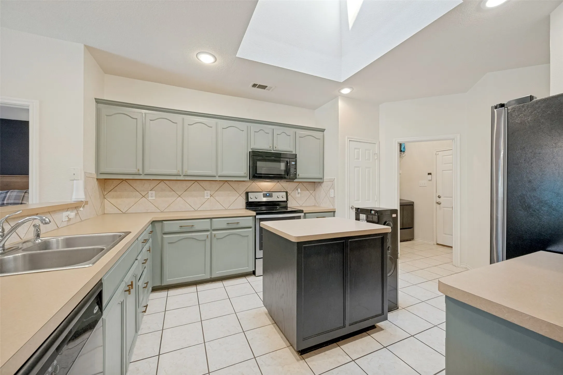 Kitchen with light-toned cabinetry, a central island, a skylight, and recessed lighting