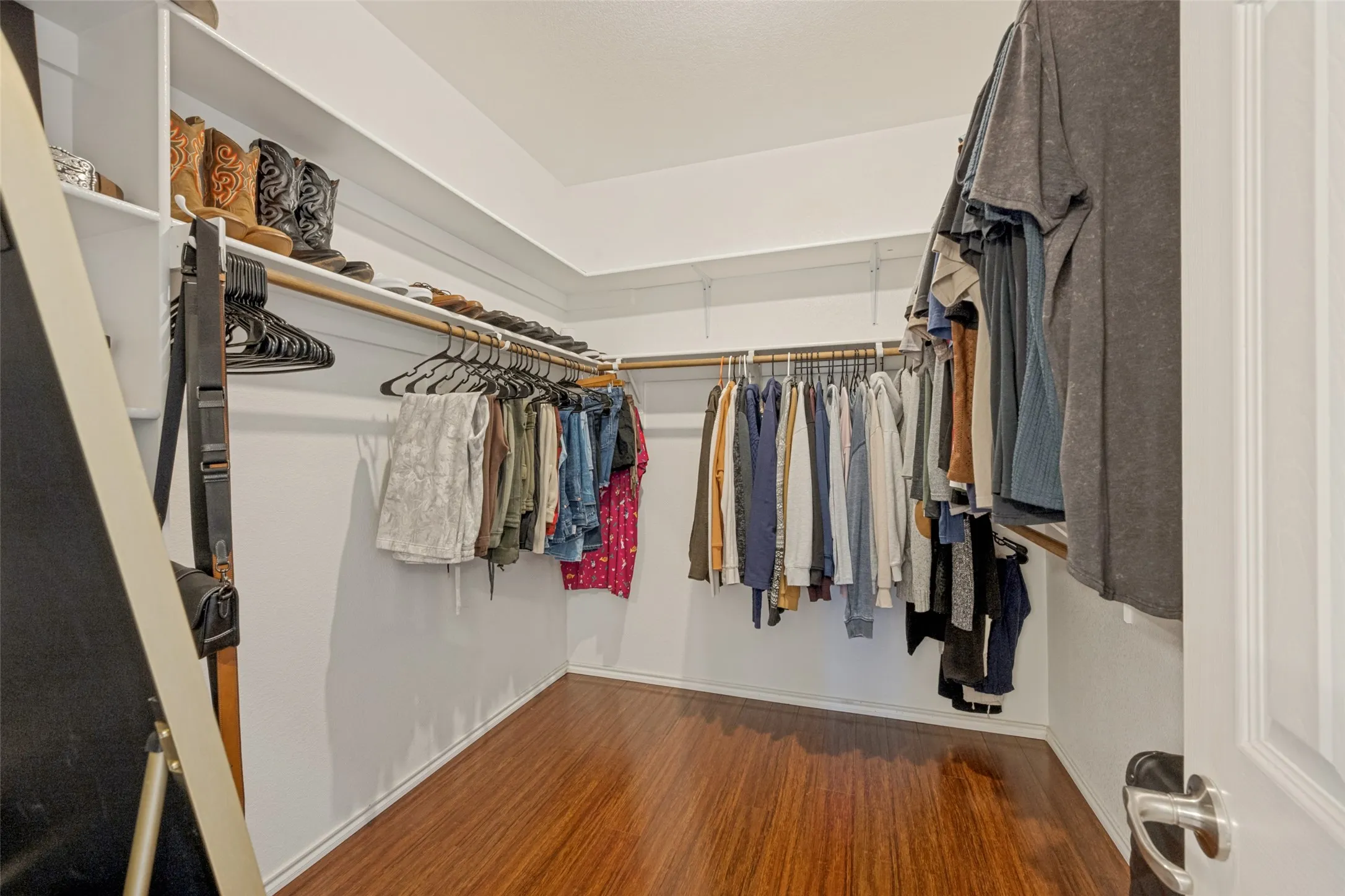 White built-in shelving, wood-finish flooring, and multiple clothing rods