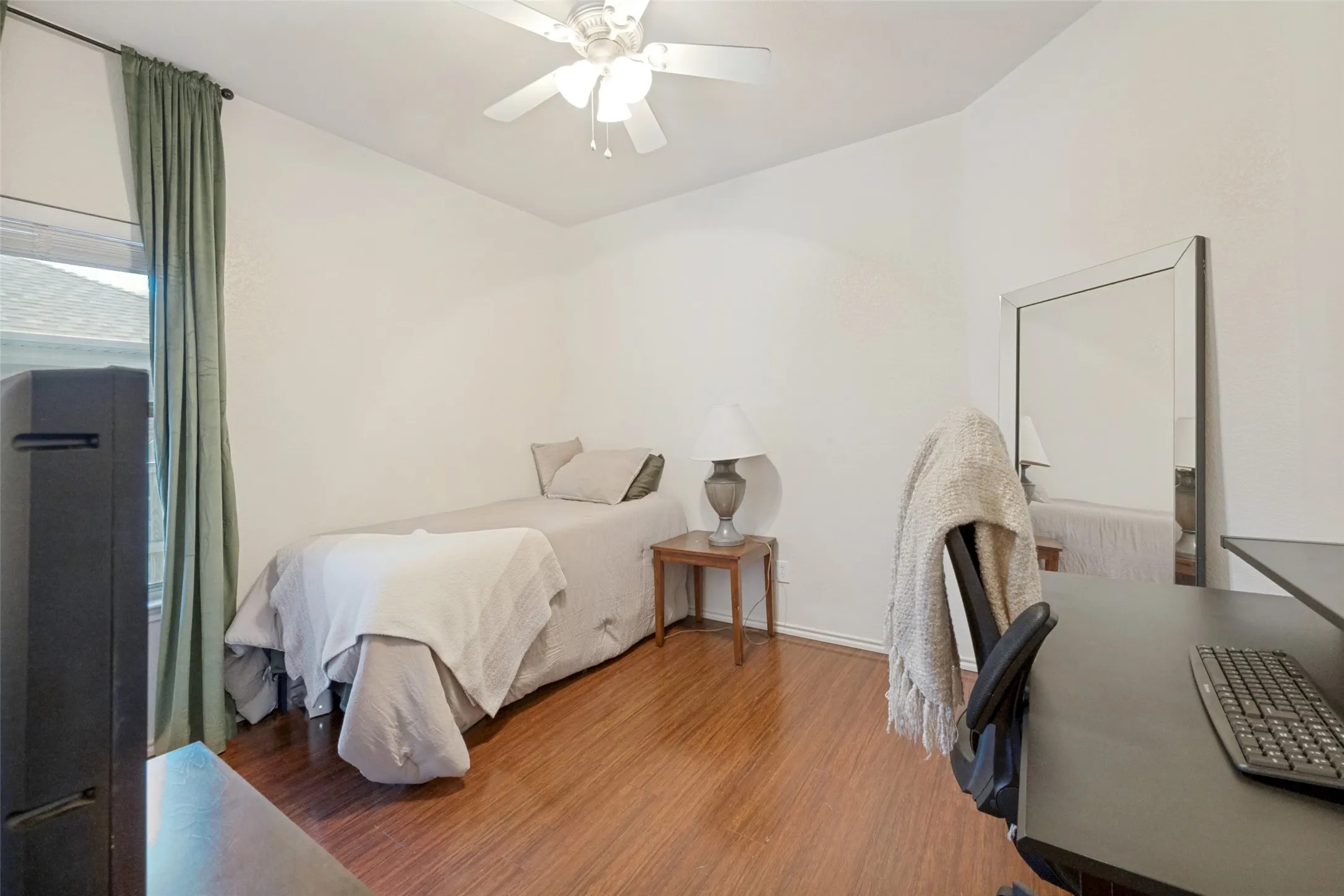 Wood-finish flooring, ceiling fan, and window with drapes