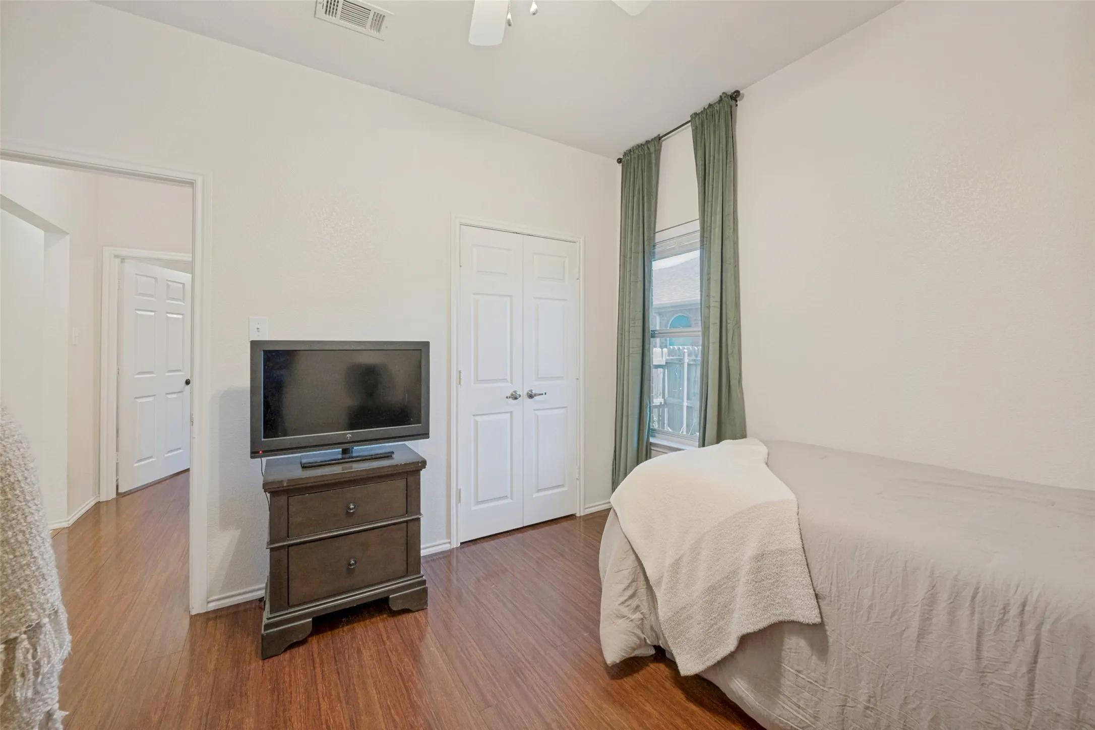 Wood-finish flooring throughout the room, featuring a double-door closet with polished hardware