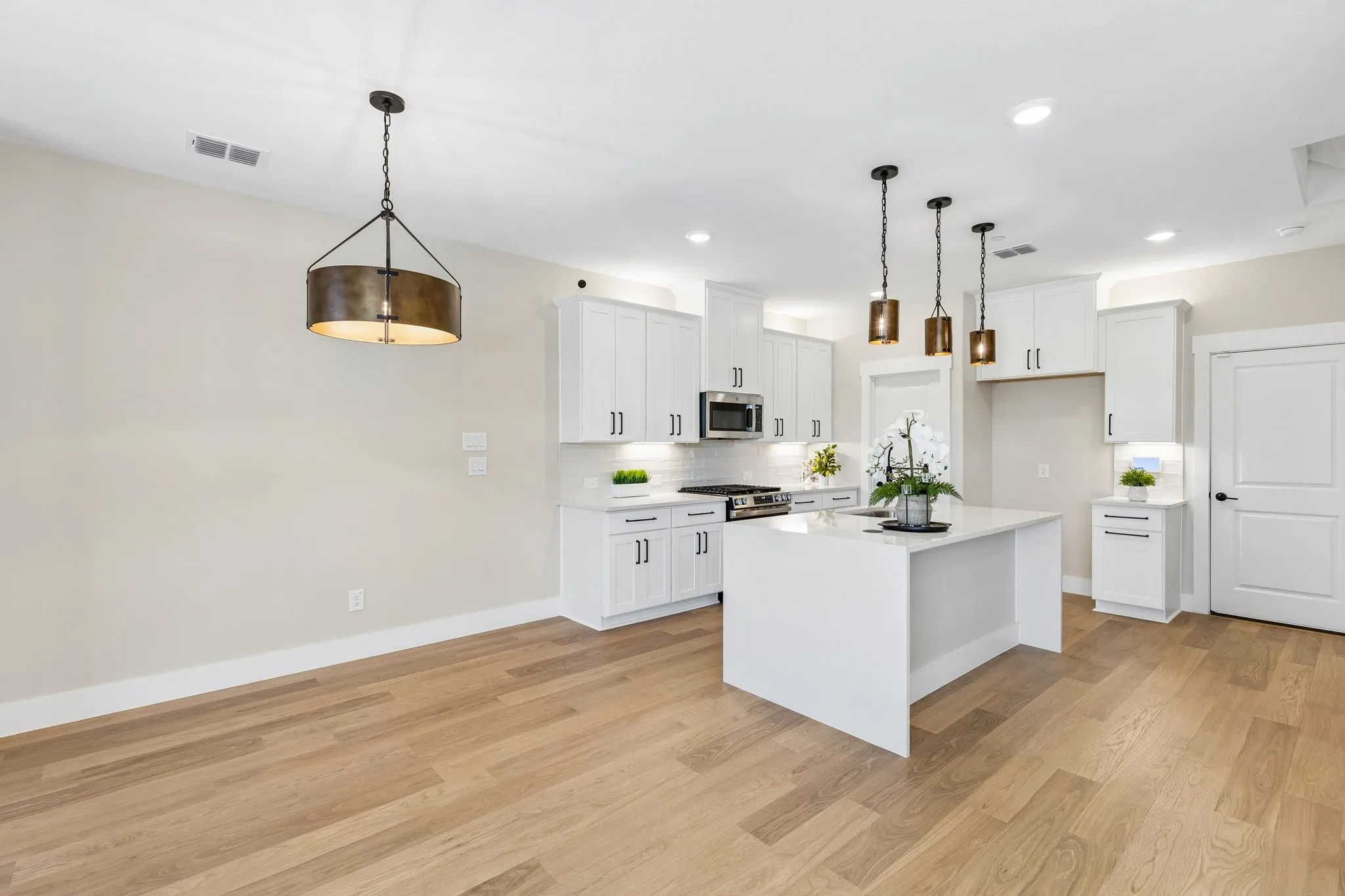 White shaker cabinetry, wood-finish flooring, recessed lighting, and a kitchen island with pendant lighting