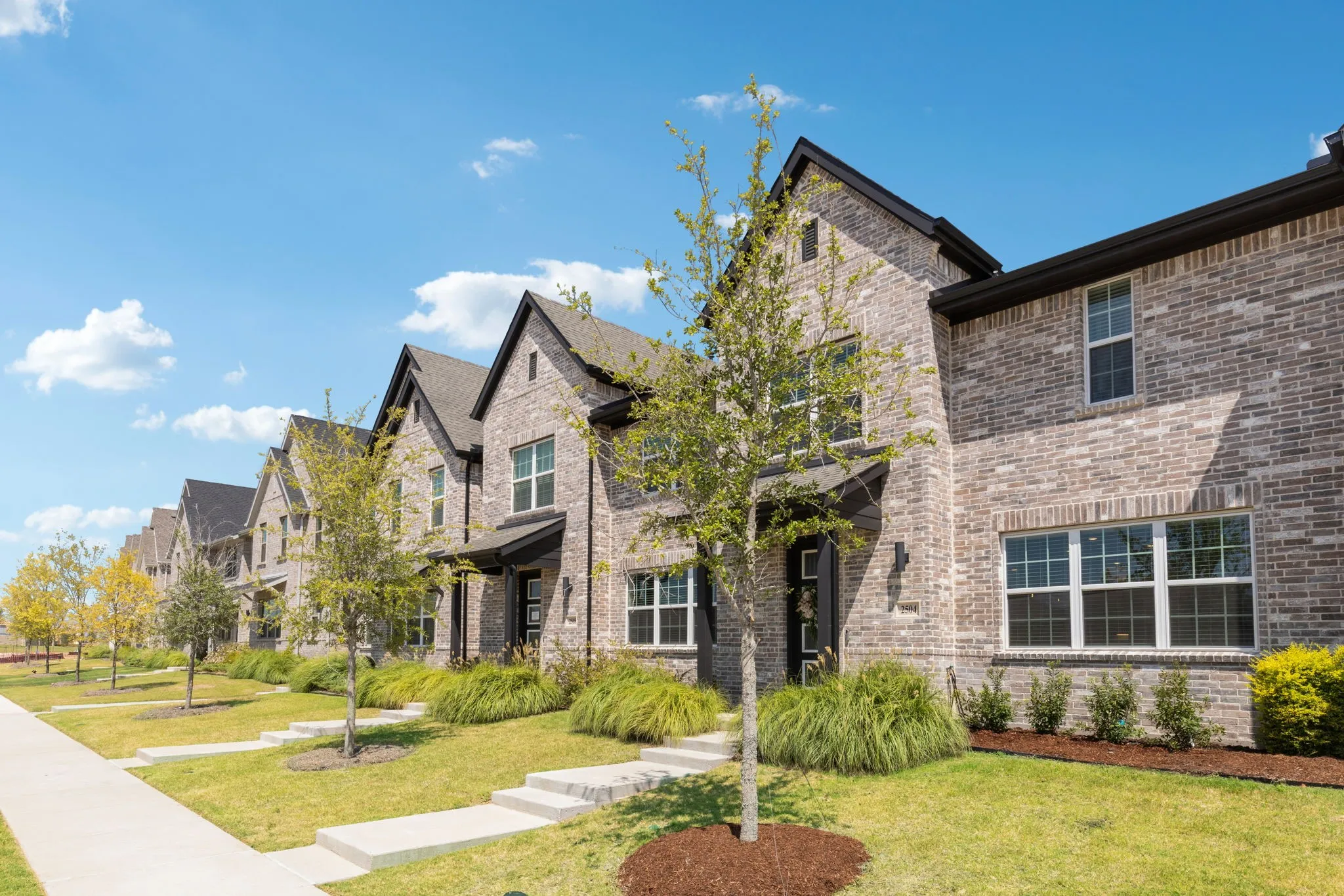 Brick exterior with dark-trimmed windows, covered entry, and pitched rooflines