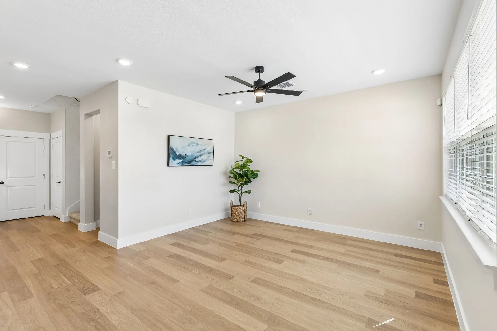Wood-finish flooring, recessed lighting, ceiling fan, white paneled doors, and window with blinds