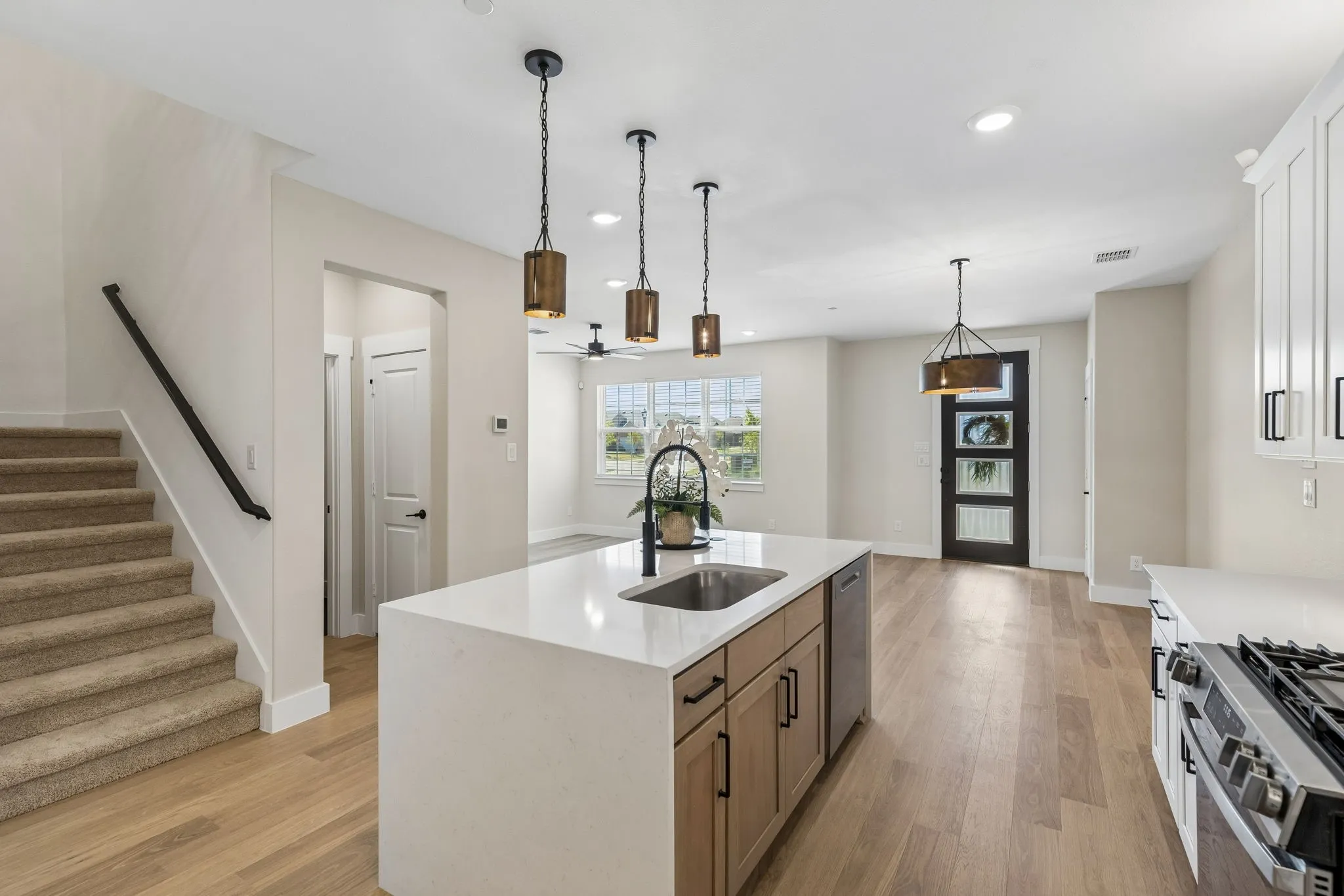Kitchen island with an undermount sink, quartz countertop, and pendant lighting