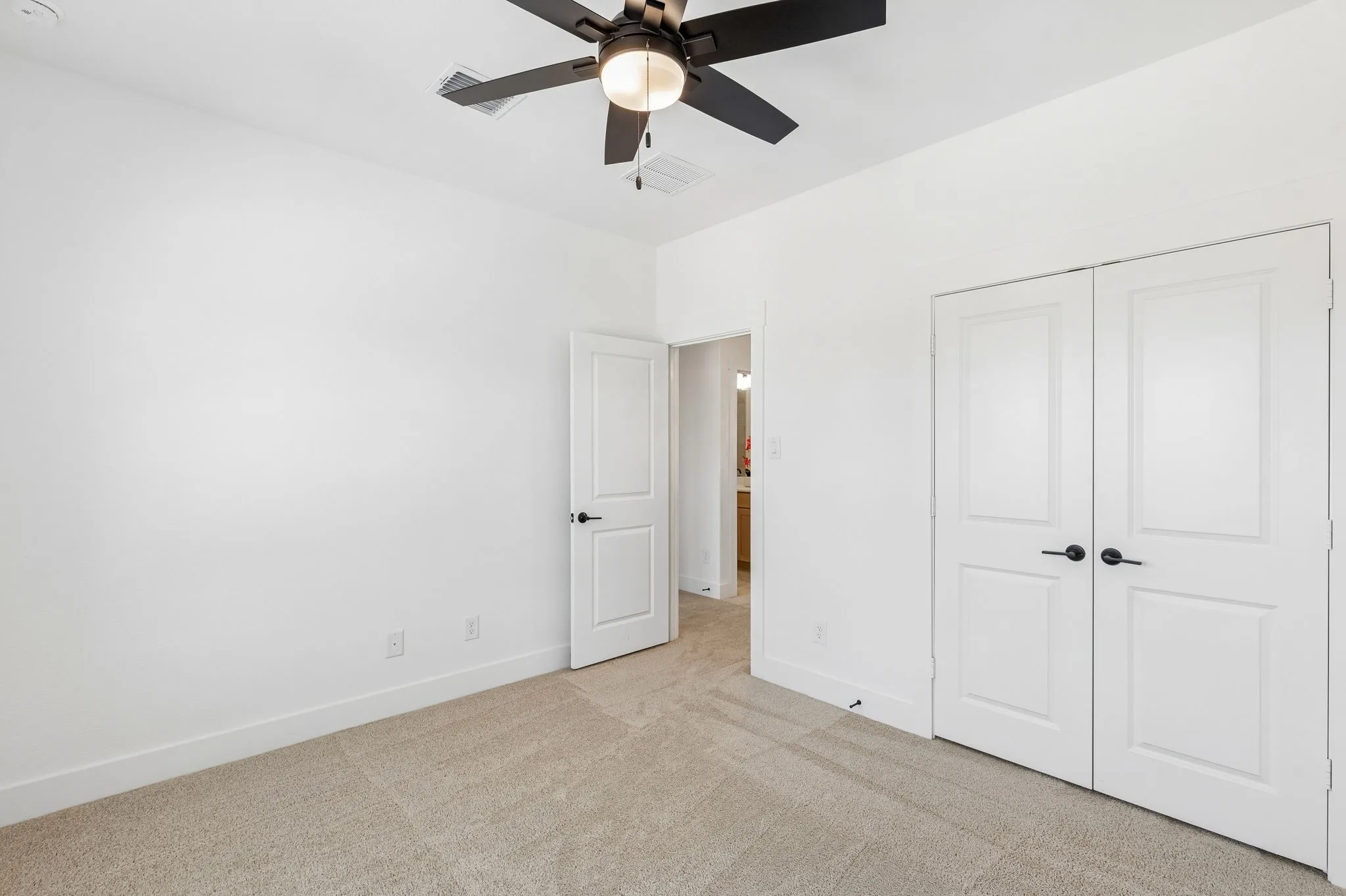 Plush carpet flooring, ceiling fan with integrated lighting, white paneled doors, and matte black hardware